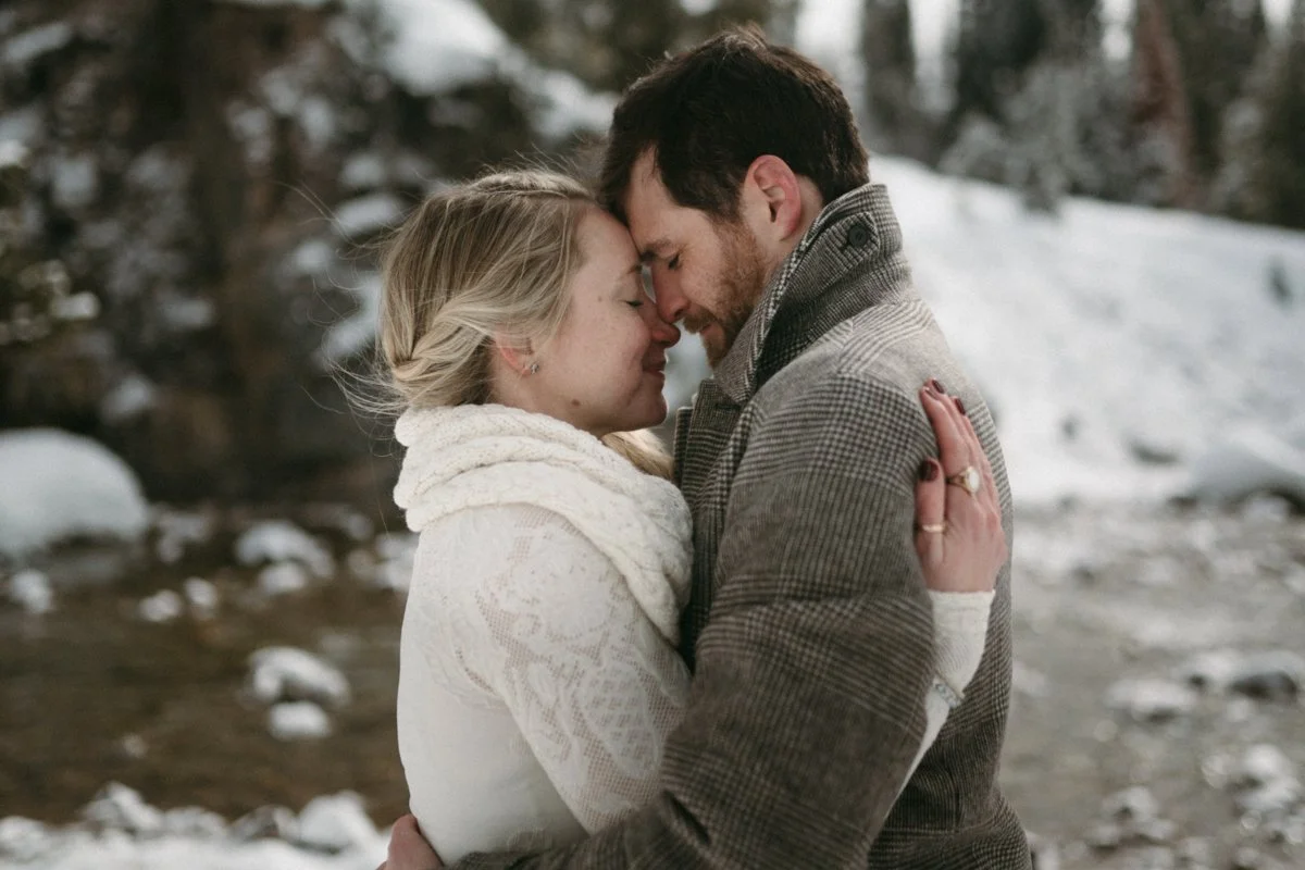 A couple stands embracing nose to nose in a snowy location after their winter wedding ceremony near Jackson Hole