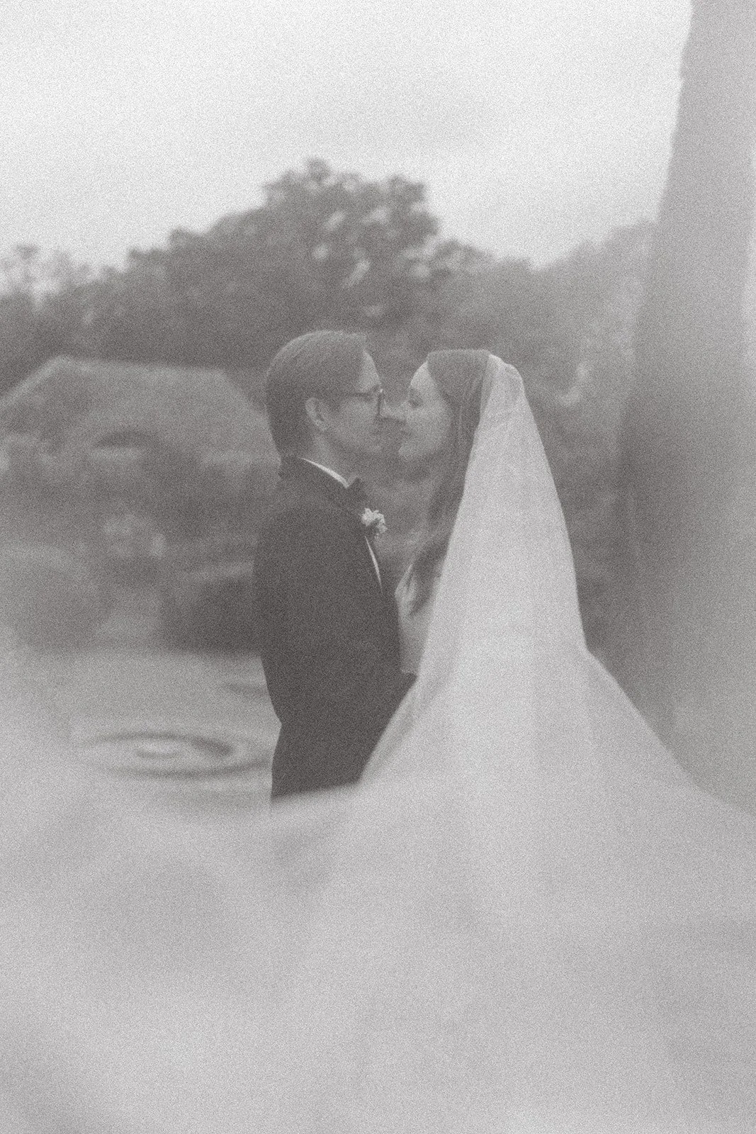 Bride with a long veil hugging her groom
