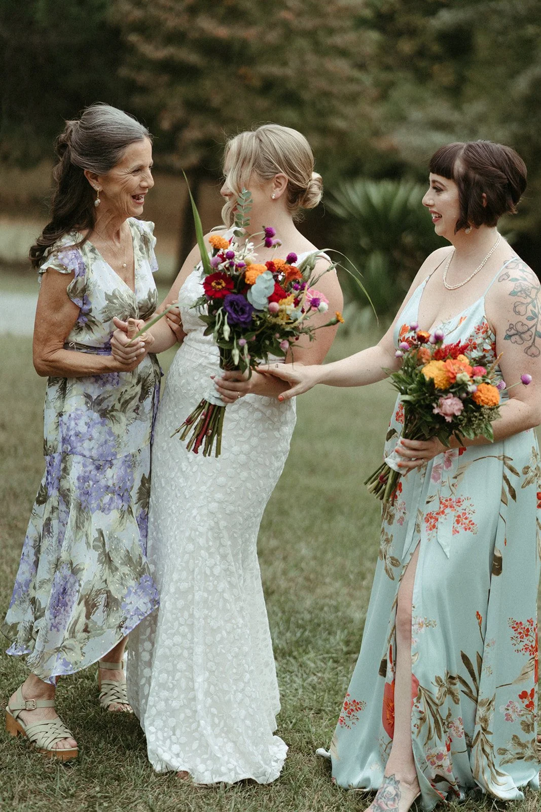 A bride with her mom and sister each with wildflower bouquets