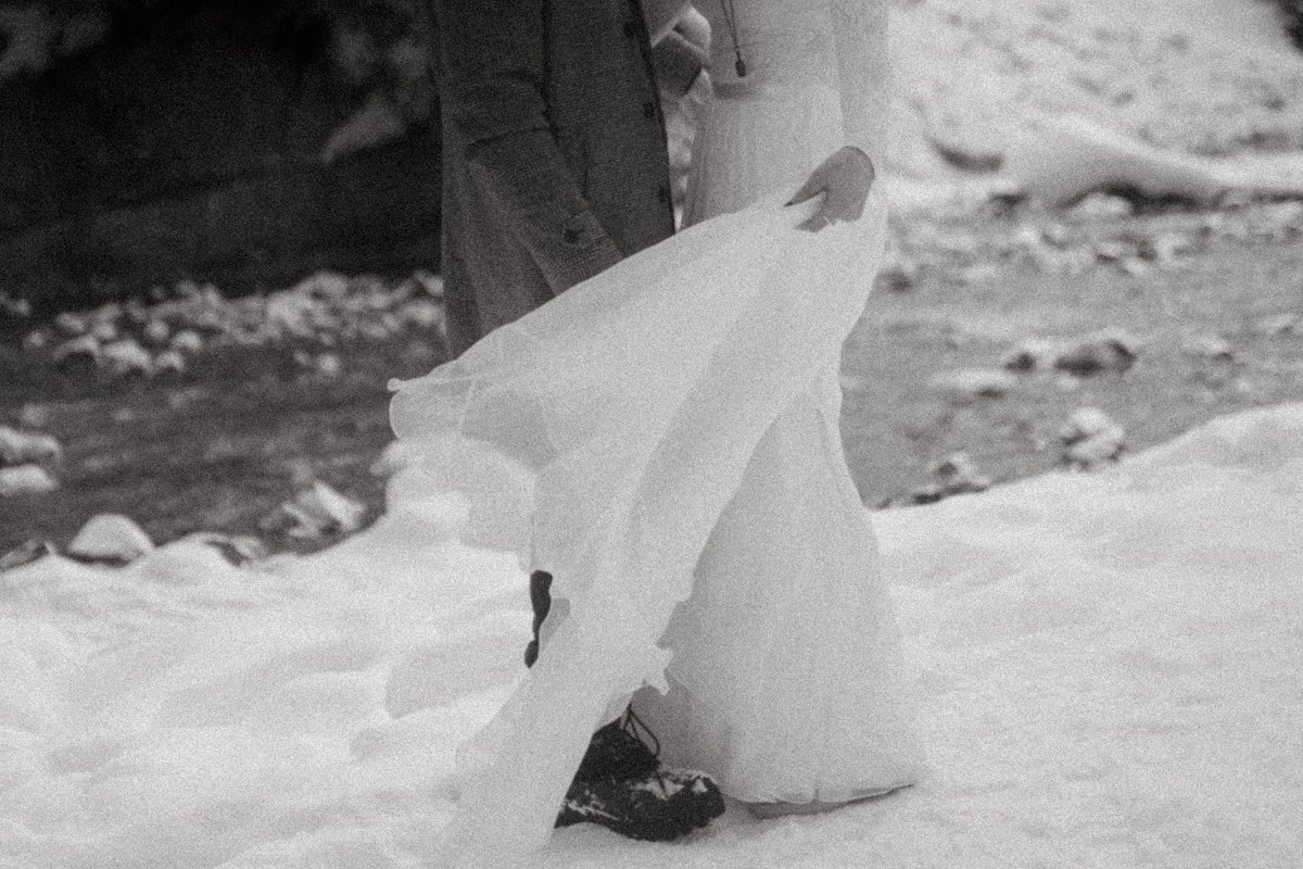 Close-up of a person holding a large piece of snow shaped into a figure, with a snowy landscape in the background.