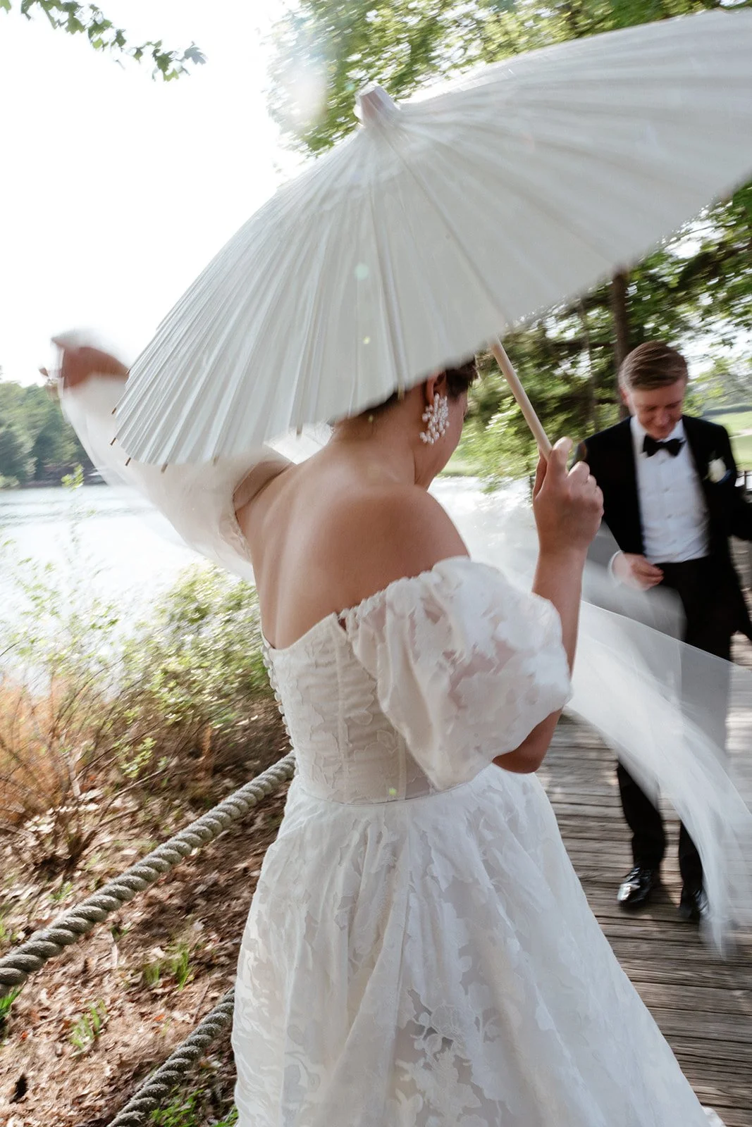 a bride holding a parasol and adjusting her veil