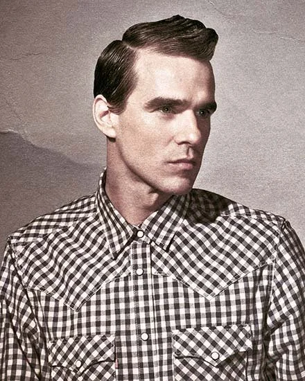 Black and white checkered shirt on a man with neatly styled hair, looking to the side against a plain background.