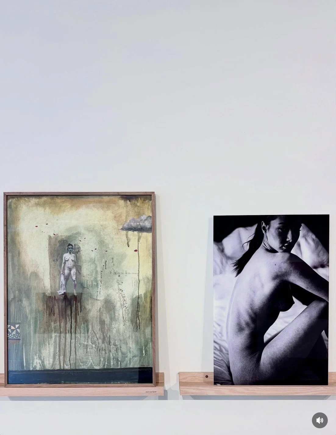 Gallery wall with various framed photographs and artworks displayed on a white wall in an art gallery.A black and white photo of a topless woman sitting on a bed, looking over her shoulder.fine art photograph, Alvaro Alcazar Gallery