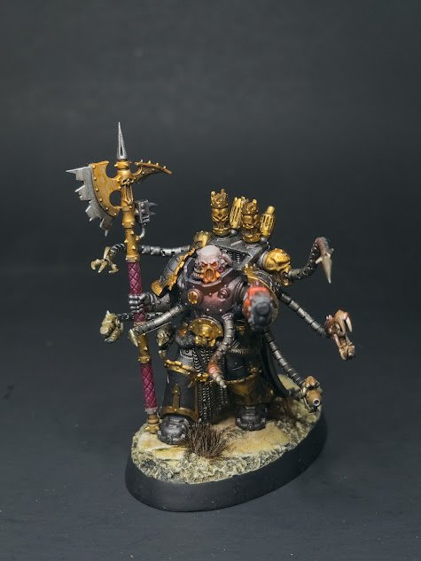 Miniature figure of a fantasy warrior with multiple arms, weapons, skull accessories, and armor, standing on a round base.