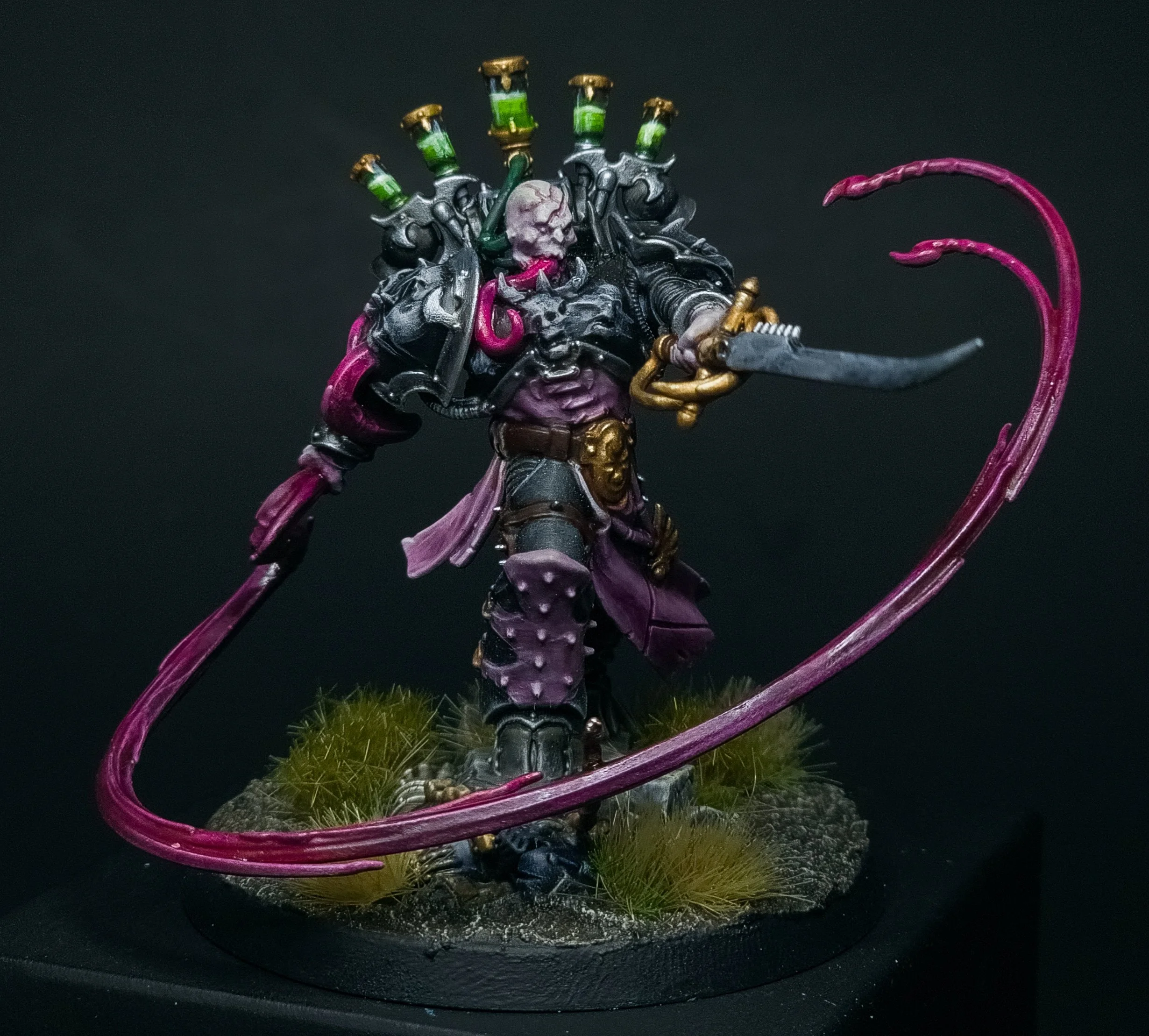 A miniature figurine of a humanoid character with skull face, black armor, pink tentacle-like accents, holding a sword, surrounded by pink tentacle-like tendrils and greenery on a base.