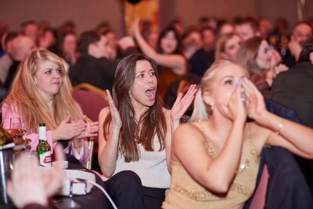 Audience members at a live event showing surprise and excitement
