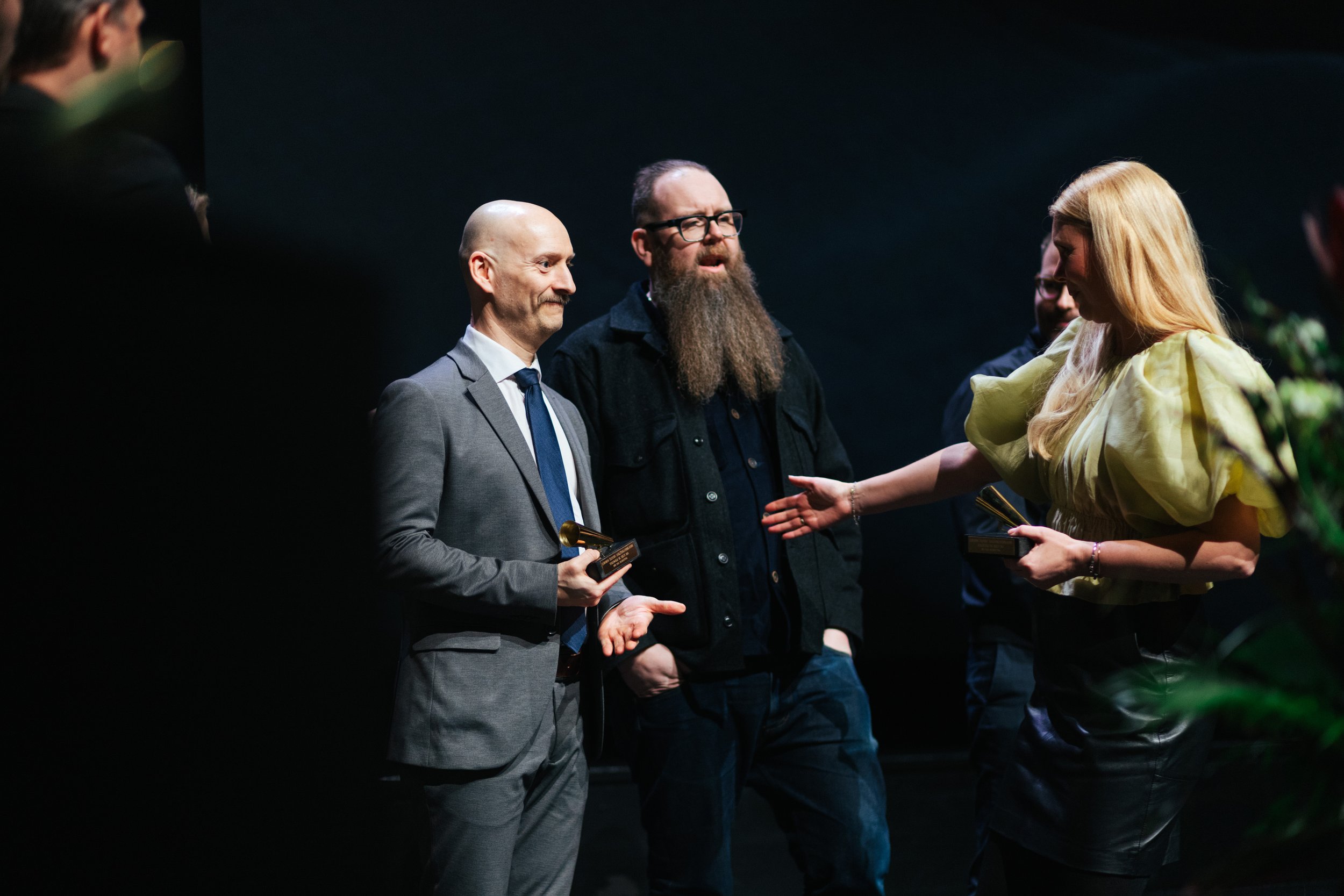 Man in a suit receiving an award from woman in a yellow dress on stage