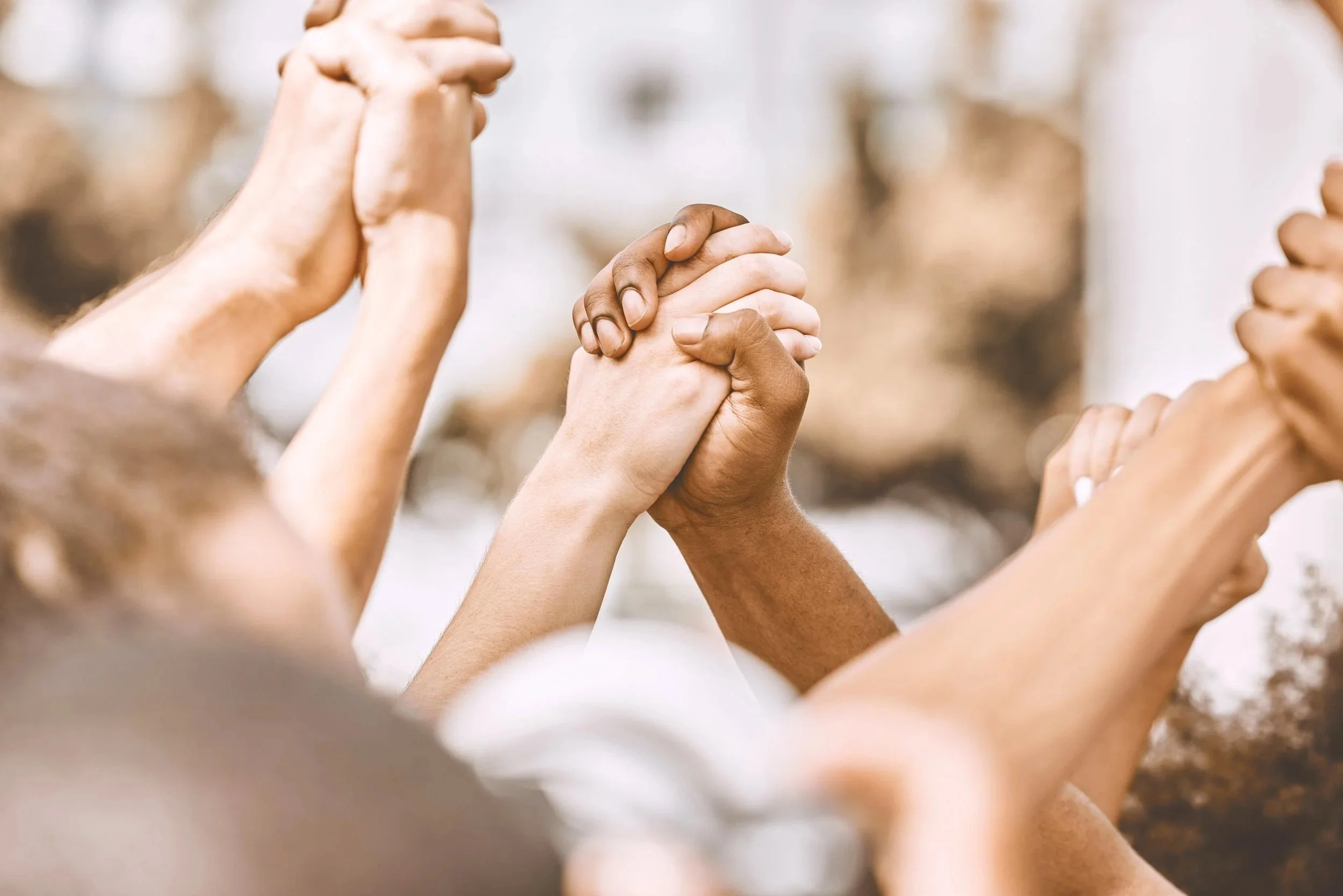 Multiple hands of diverse skin tones joining in a display of unity and teamwork.