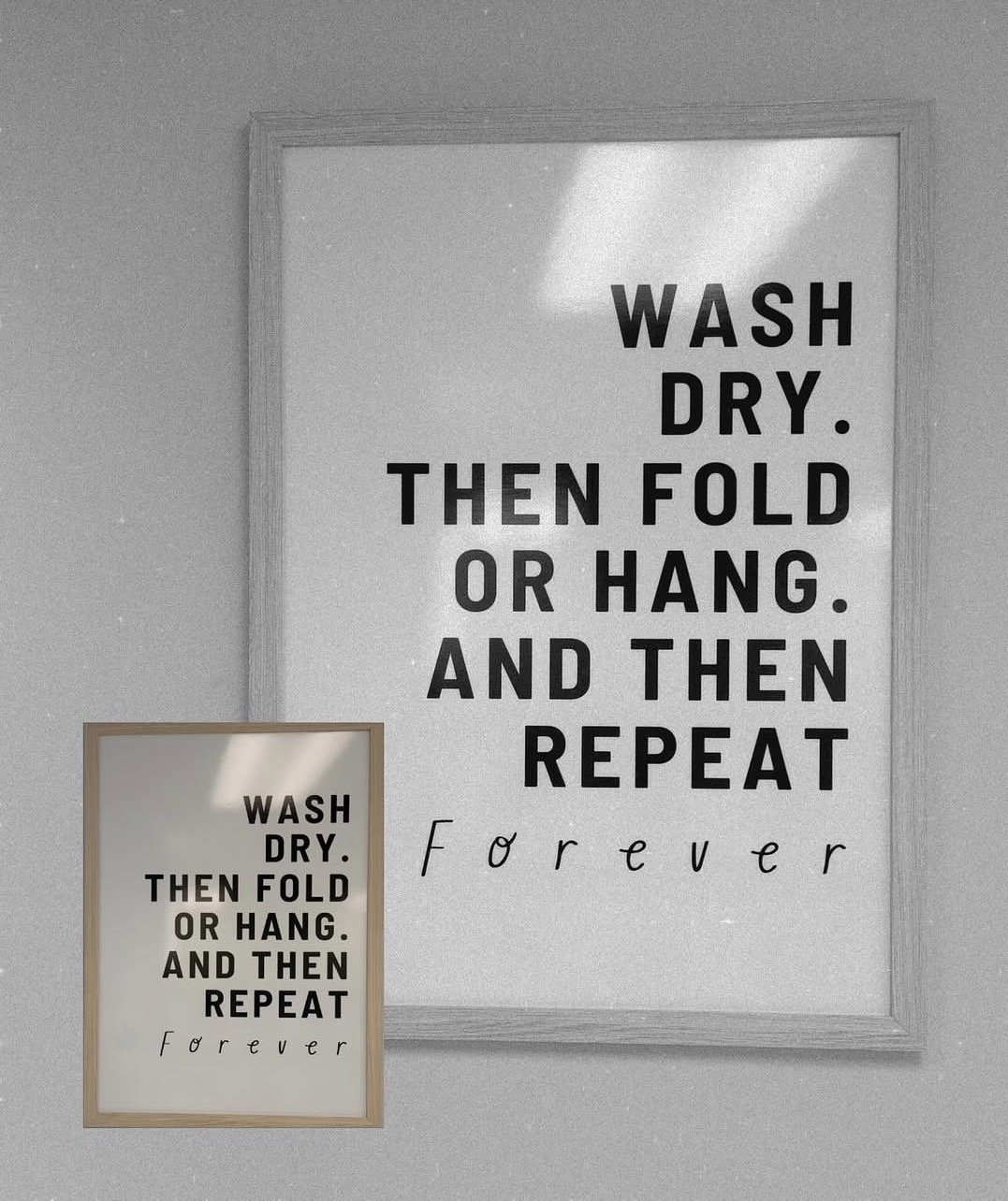 A framed wall sign with the instructions 'WASH DRY. THEN FOLD OR HANG. AND THEN REPEAT. Forever' in bold text on a light background.
