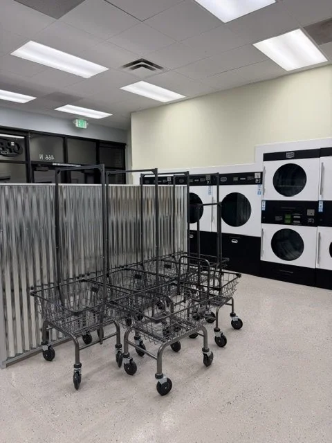 Empty shopping carts in front of dryer and washer machines in a laundromat.