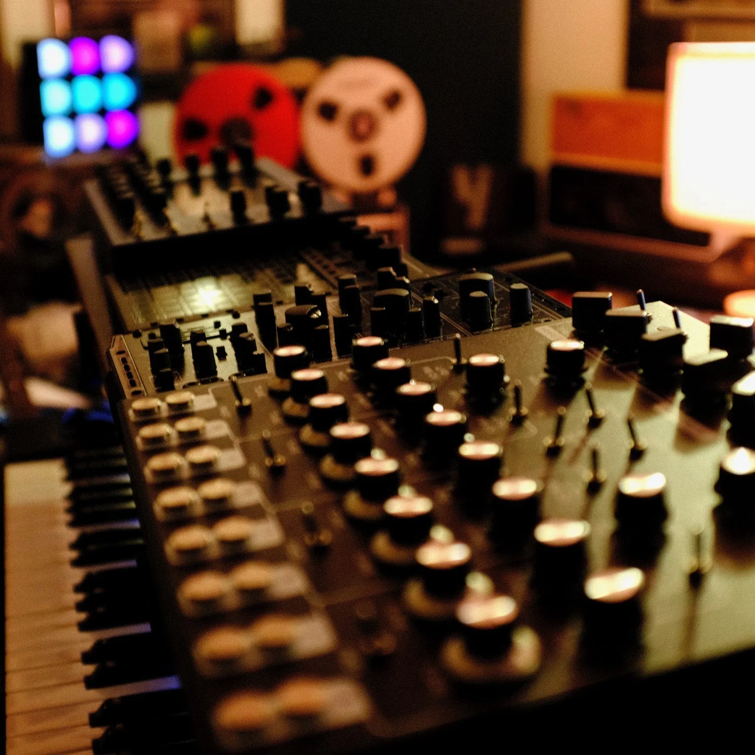 Close-up of a music mixing console with various knobs and sliders, in a dimly lit room.