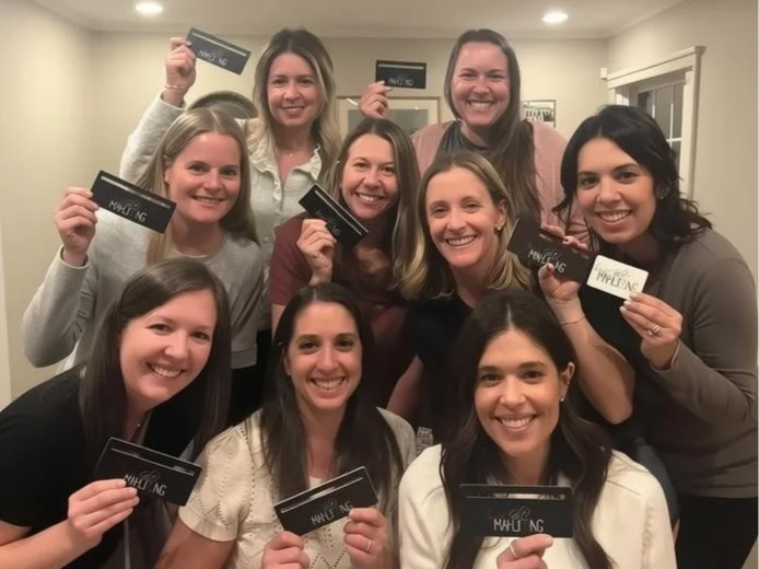 Group of ten women smiling and holding mahjong cards, mahjong group lesson