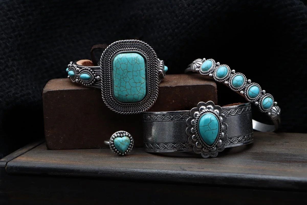 A collection of turquoise jewelry arranged on a wooden box and metal block. Shot and retouched by Sarah Crooks.