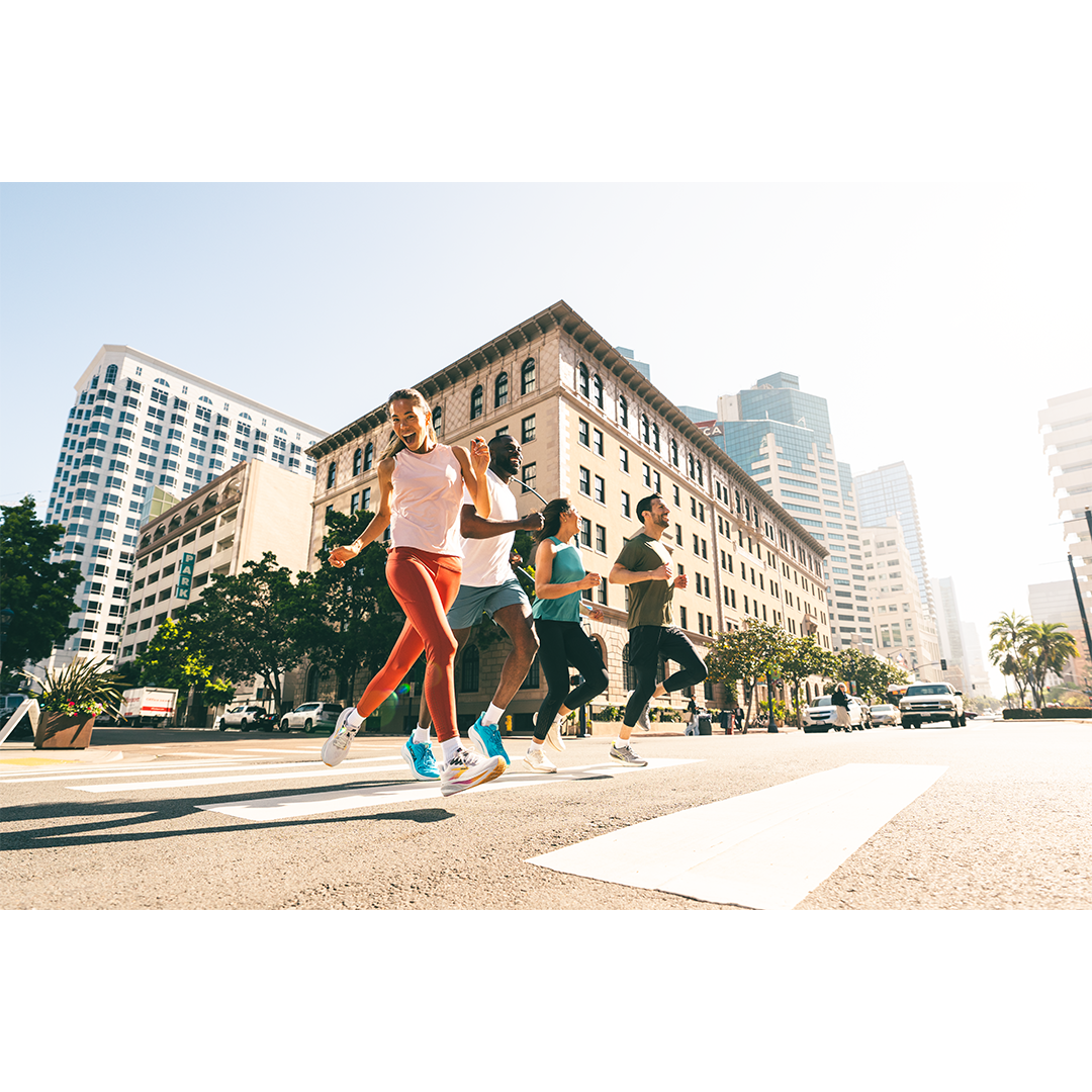 Orginal lifestyle image of a group of five people running on city street in daylight.