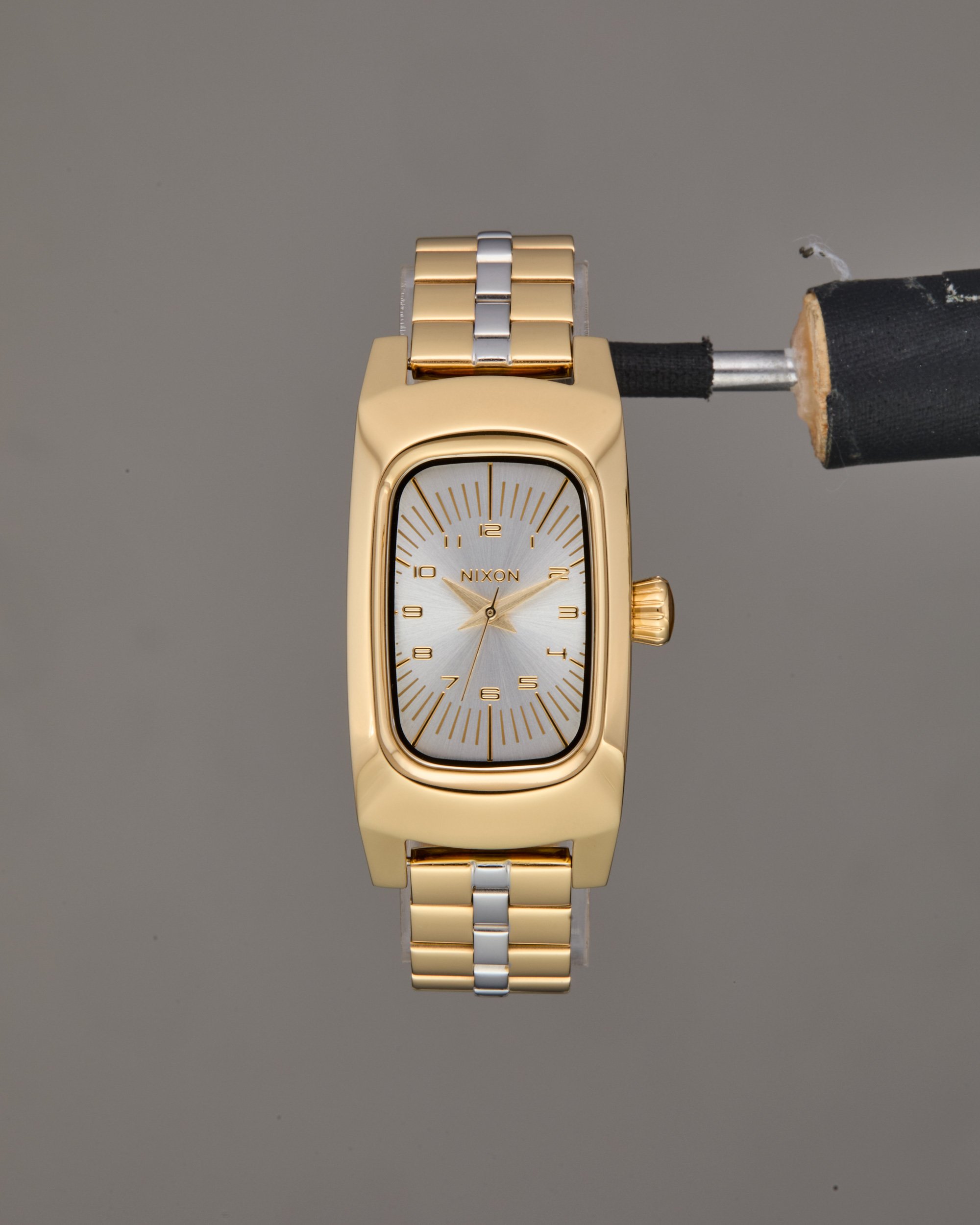 Unretouched e-commerce shot of a gold and silver Nixon Frankie wristwatch with a rectangular face and white dial displaying gold hour markers and hands.