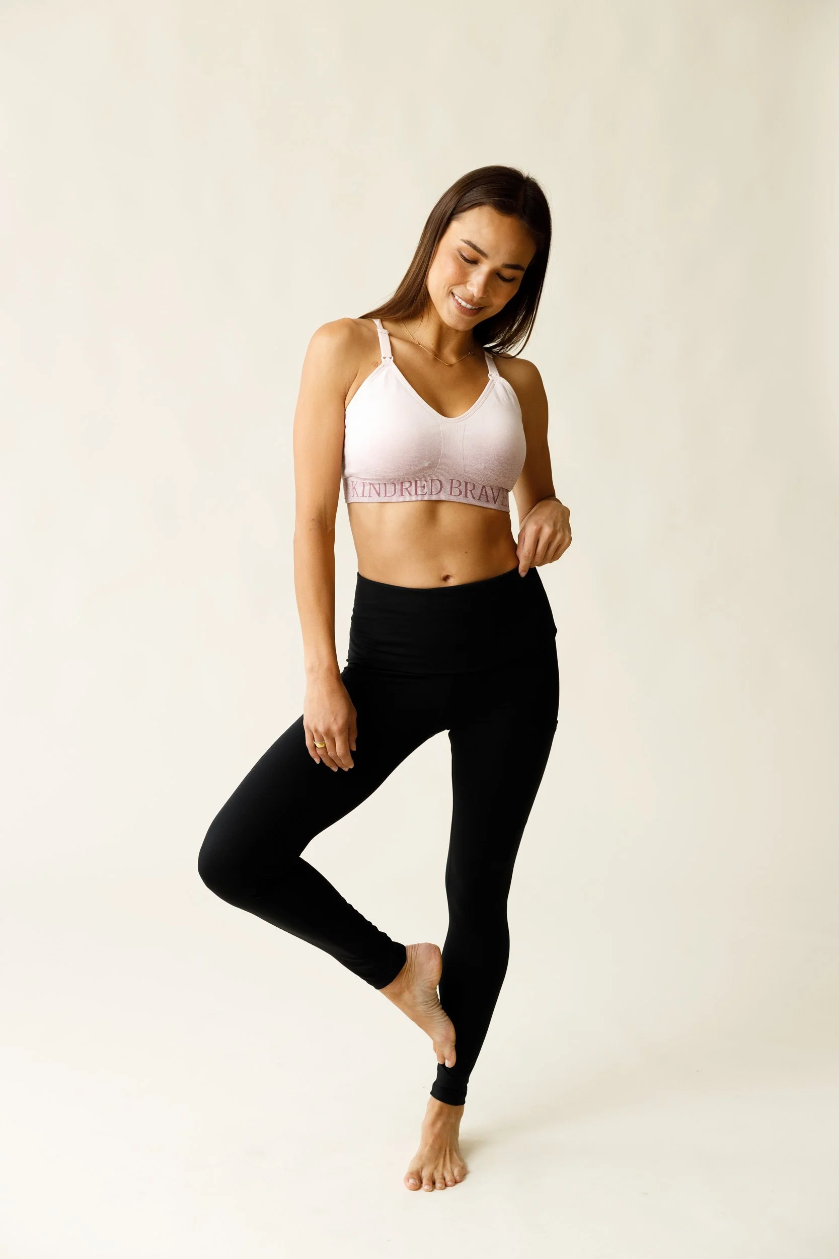 An unretouched e-commerce shot of a model in black leggings and a pink sports bra.