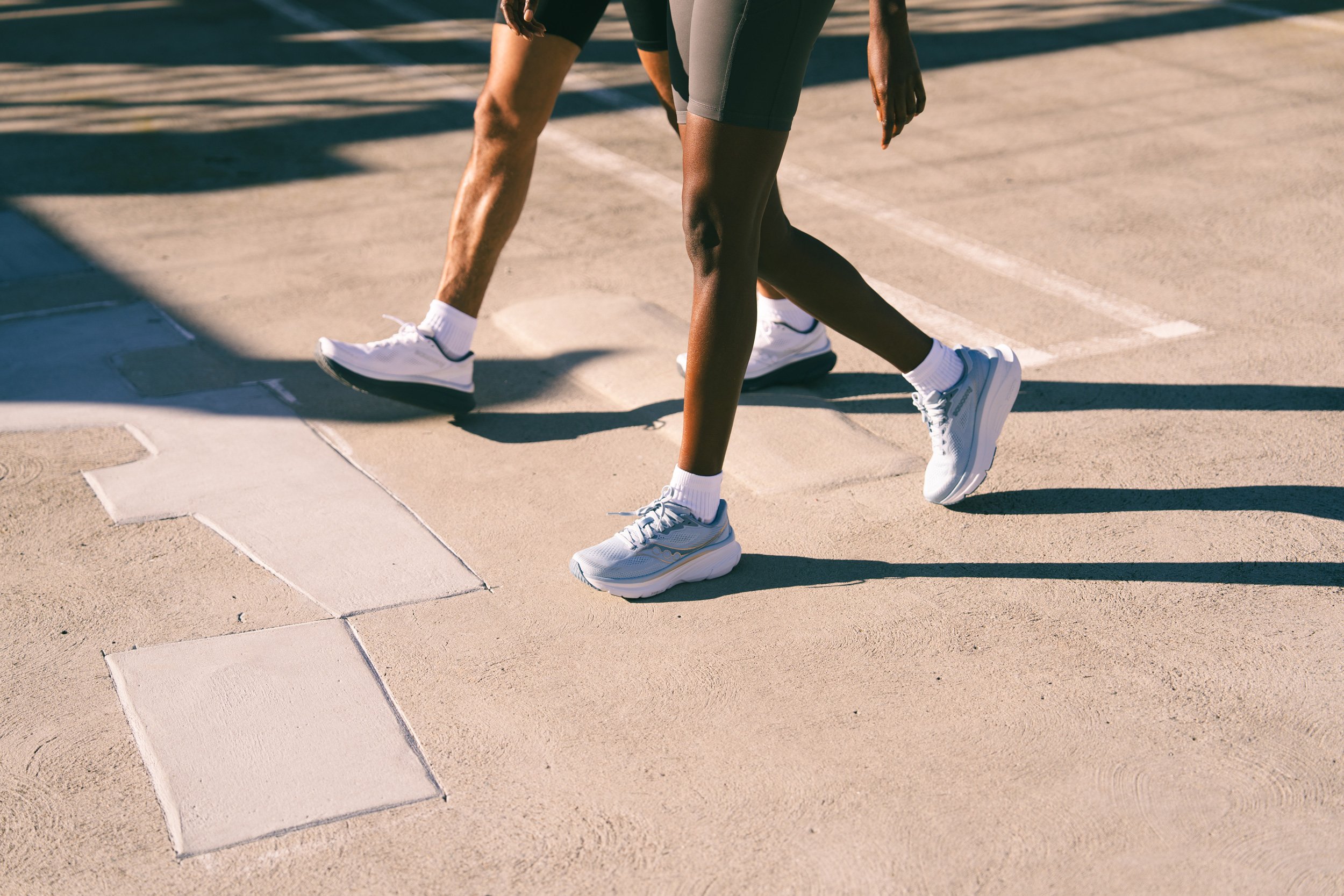 Original lifestyle shot for Road Runner Sports with a close-up of two people walking on a sidewalk.