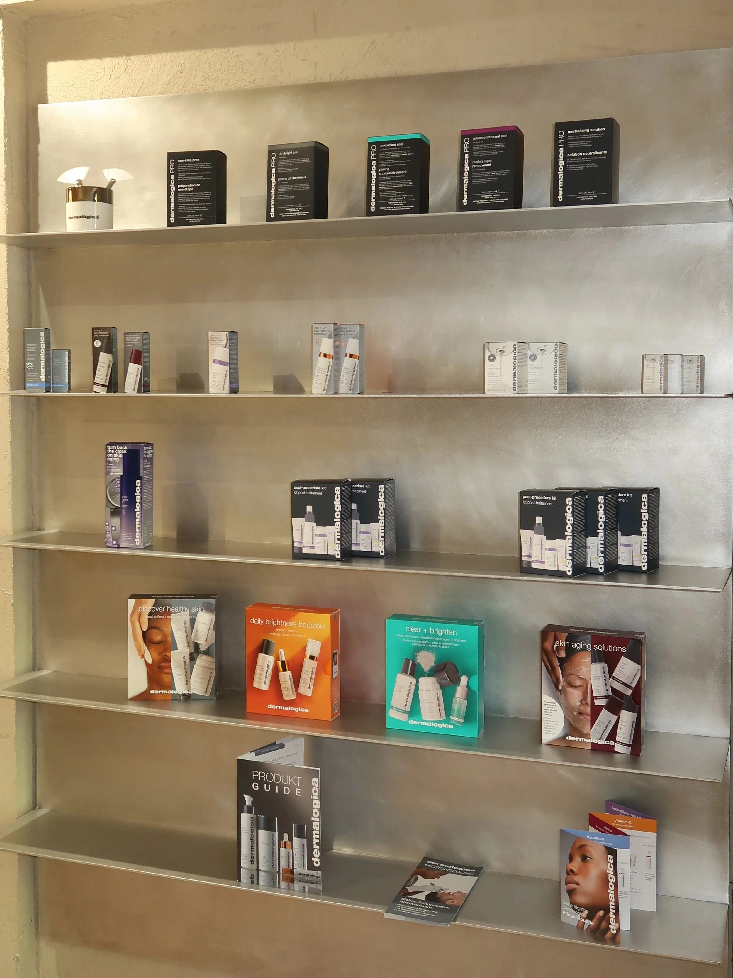 Regal mit Hautpflegeprodukten, Broschüren und Produktinformationen in einer Apotheke oder Drogerie.