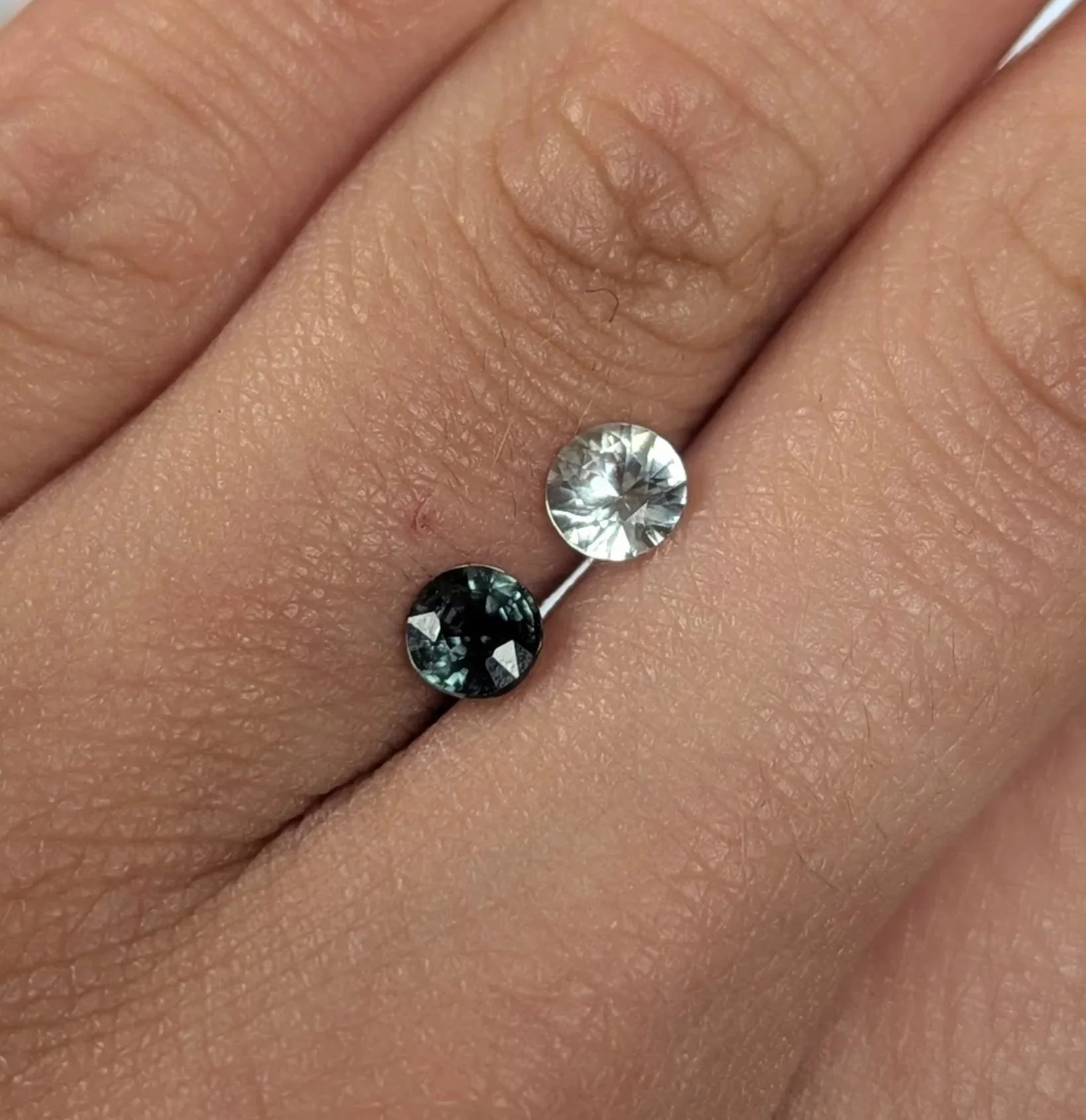 Close-up of a hand with a ring featuring three gemstones, two black and one clear, worn on the finger.
