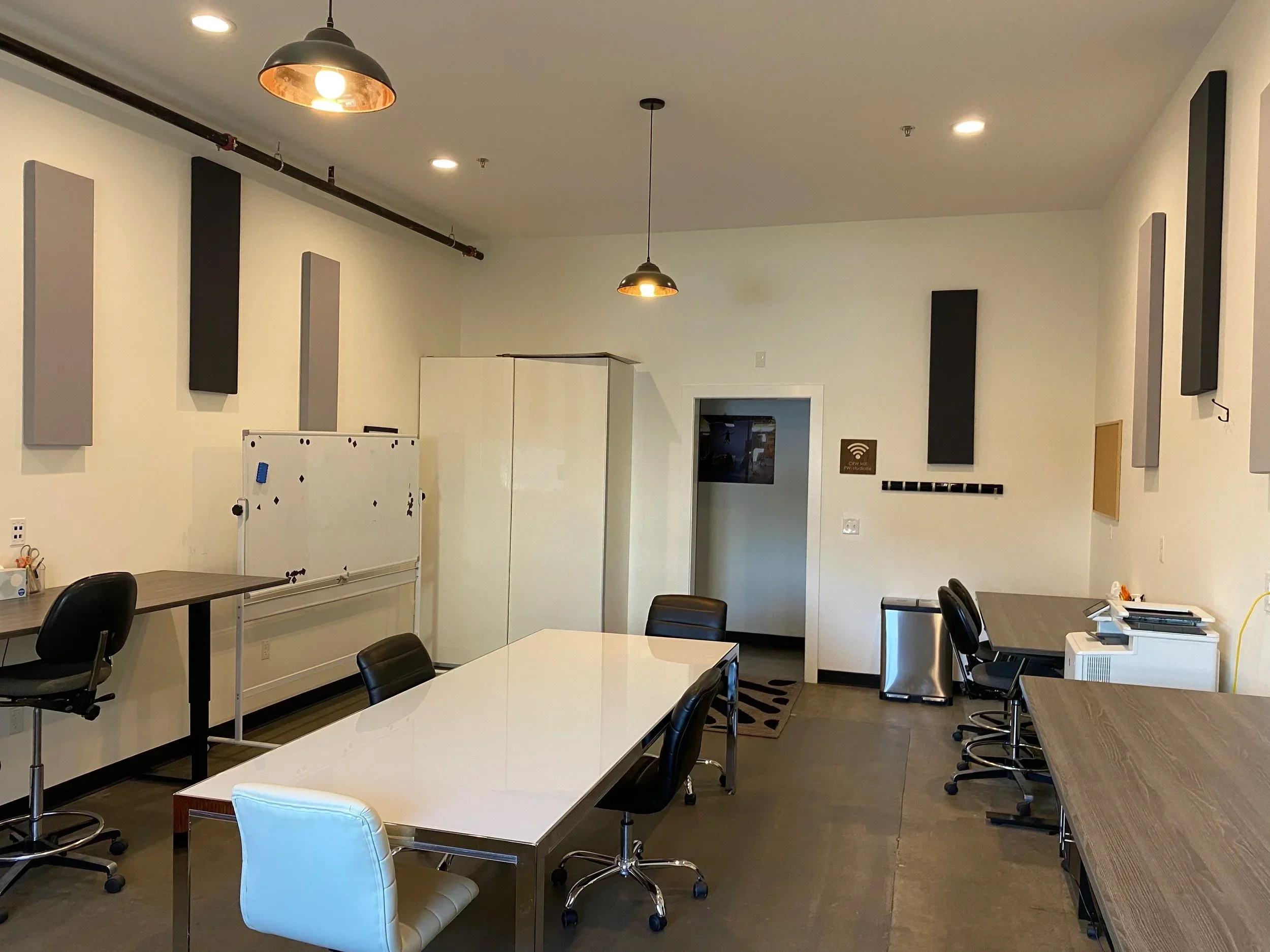 A spacious production office with a large table and multiple workstations.