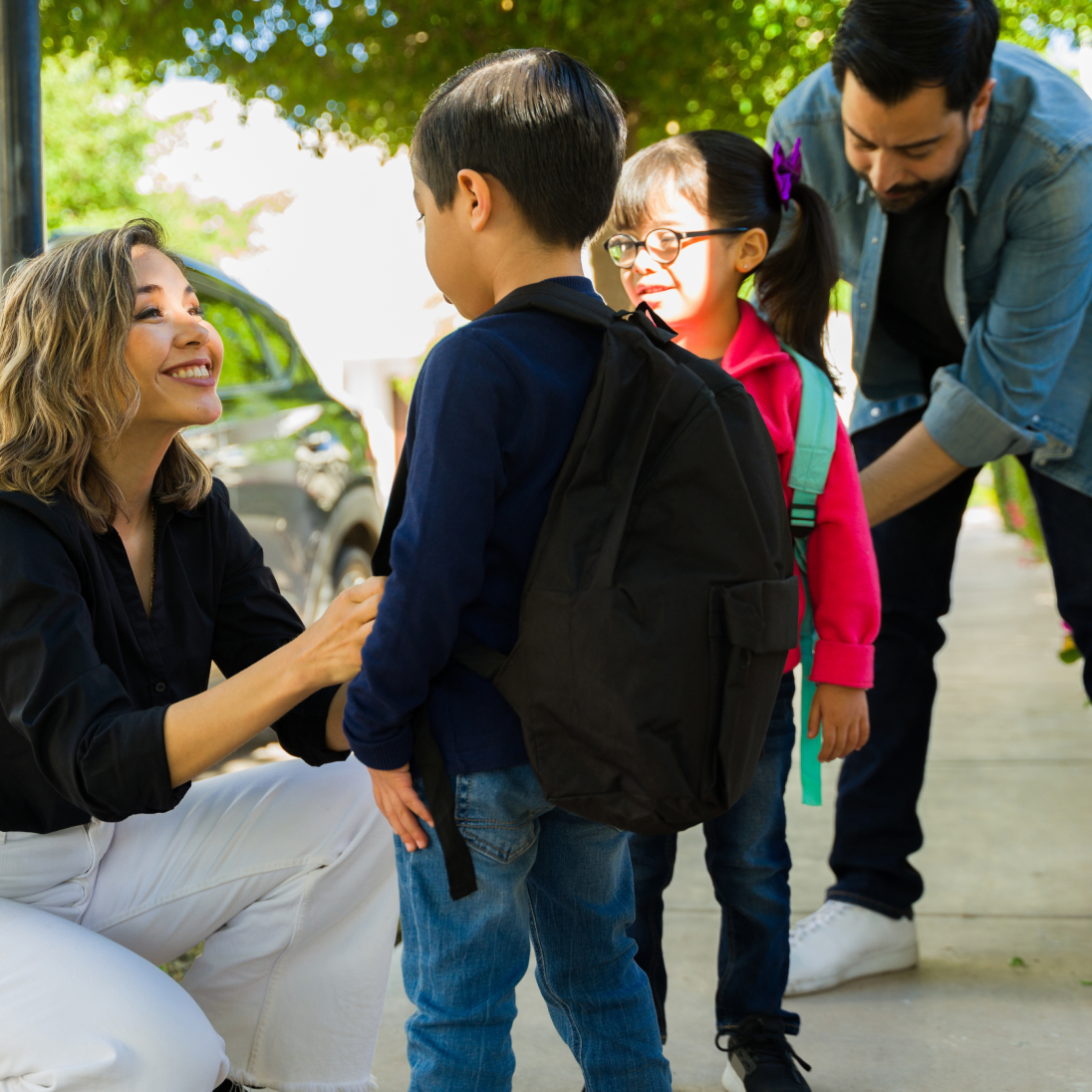A family getting ready for school. It has a mom a dad and two children with backpacks