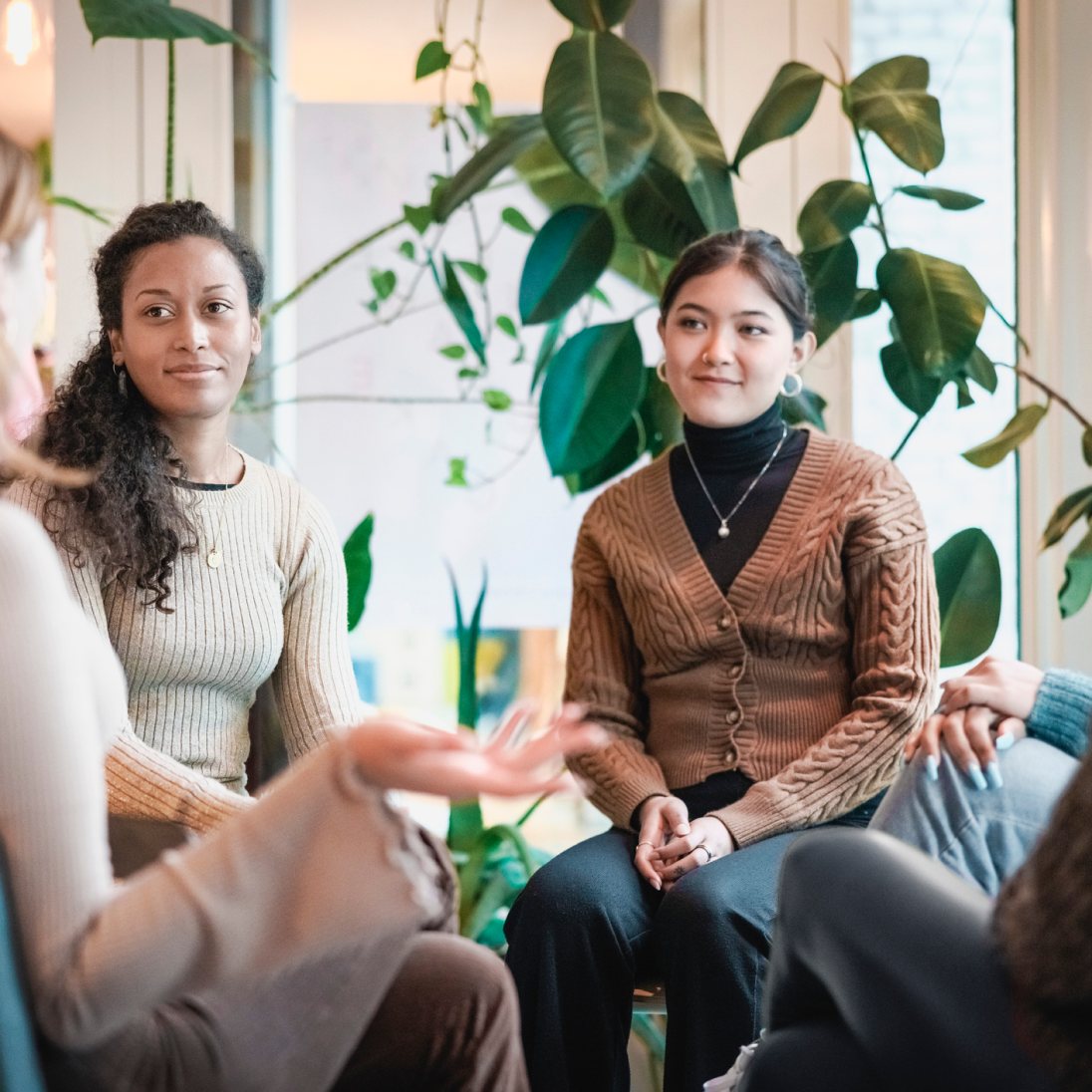 a group of young women sitting in a community group talking to one another