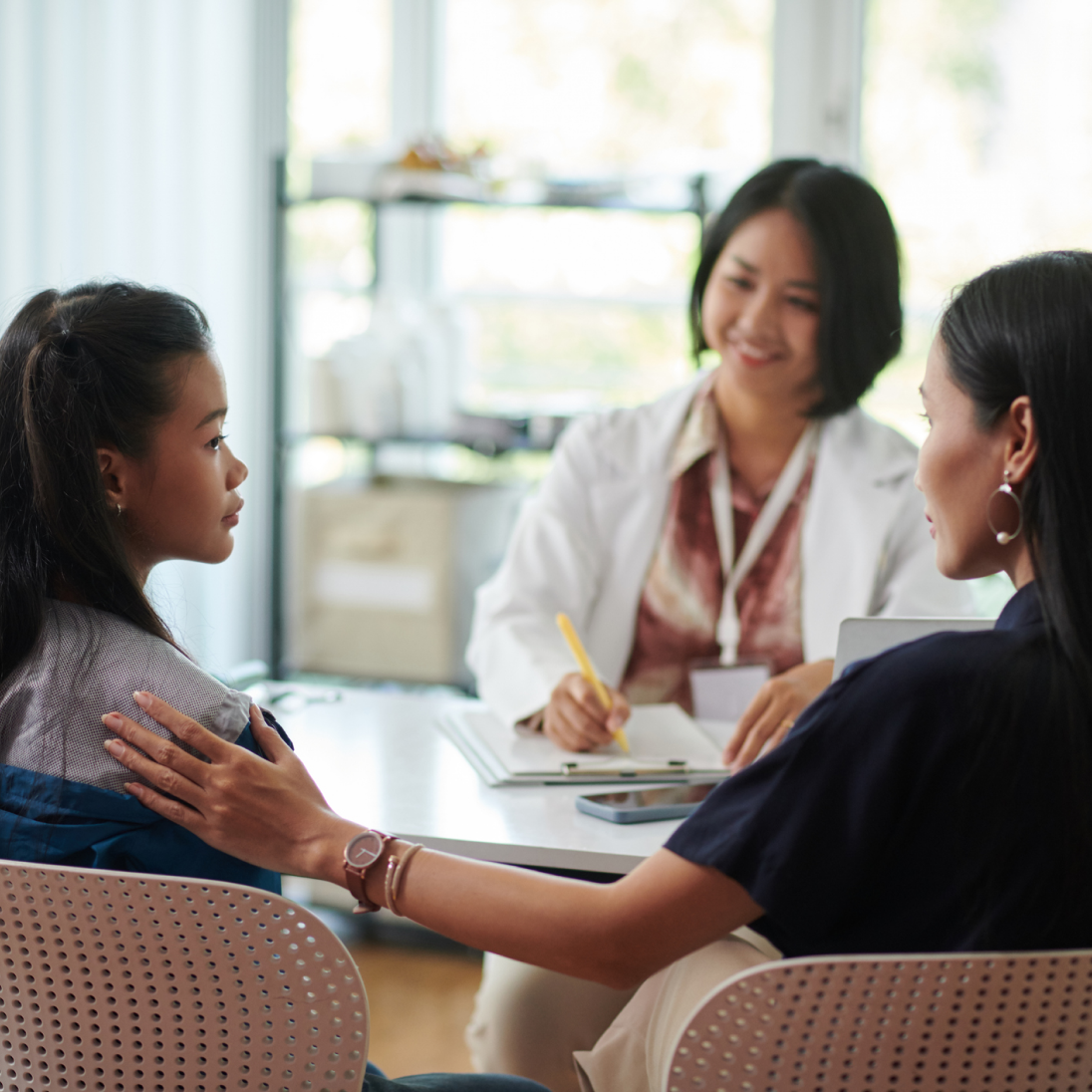 a woman and her daughter talking to another woman that could be a school counselor
