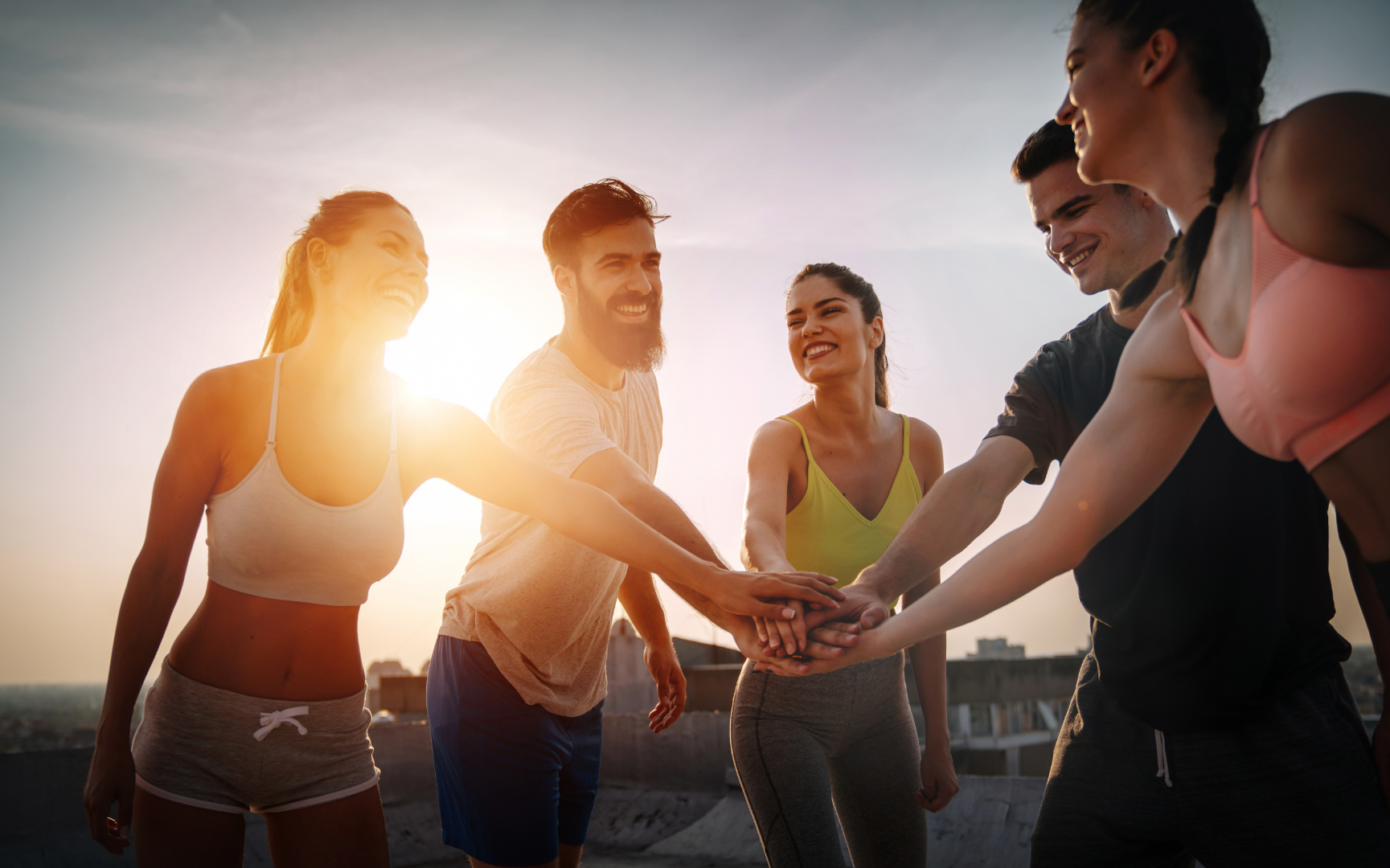 Fitness group joining hands together, symbolizing shared commitment to building a stronger body, stronger mind, and stronger life through consistent daily action.