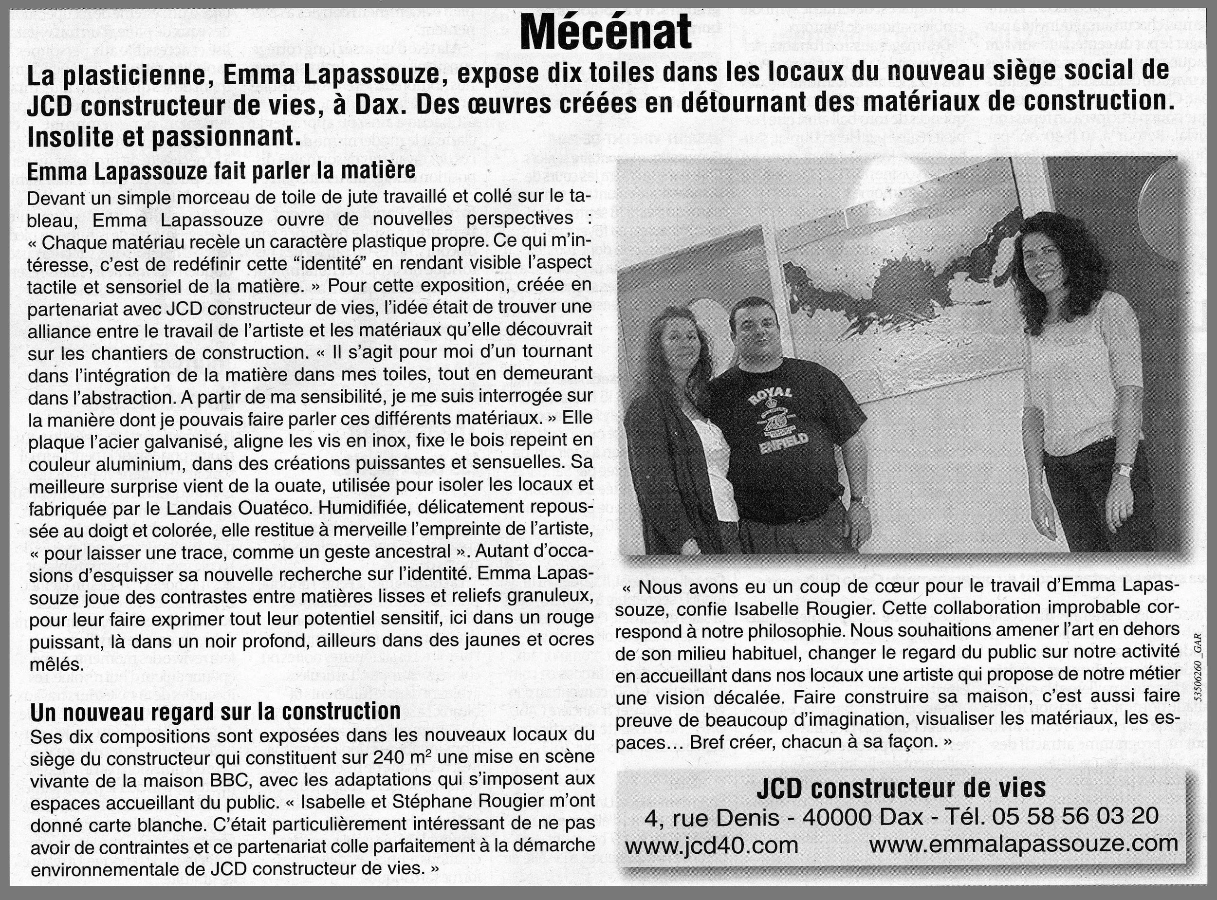Une photo en noir et blanc de trois personnes posant devant deux œuvres d'art abstraites dans une galerie ou un espace d'exposition. Une femme souriante à droite, un homme au centre, et une femme à gauche portant une veste noire.