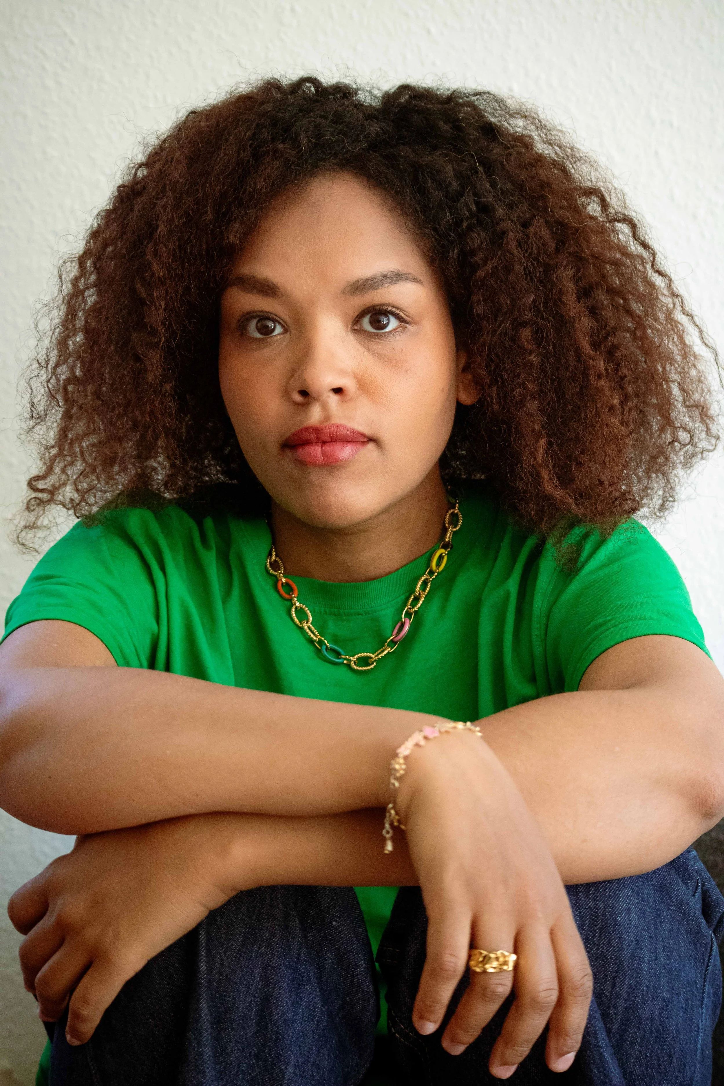 Portrait d'Aurélia Durand, t-shirt vert, bijoux, cheveux afro
