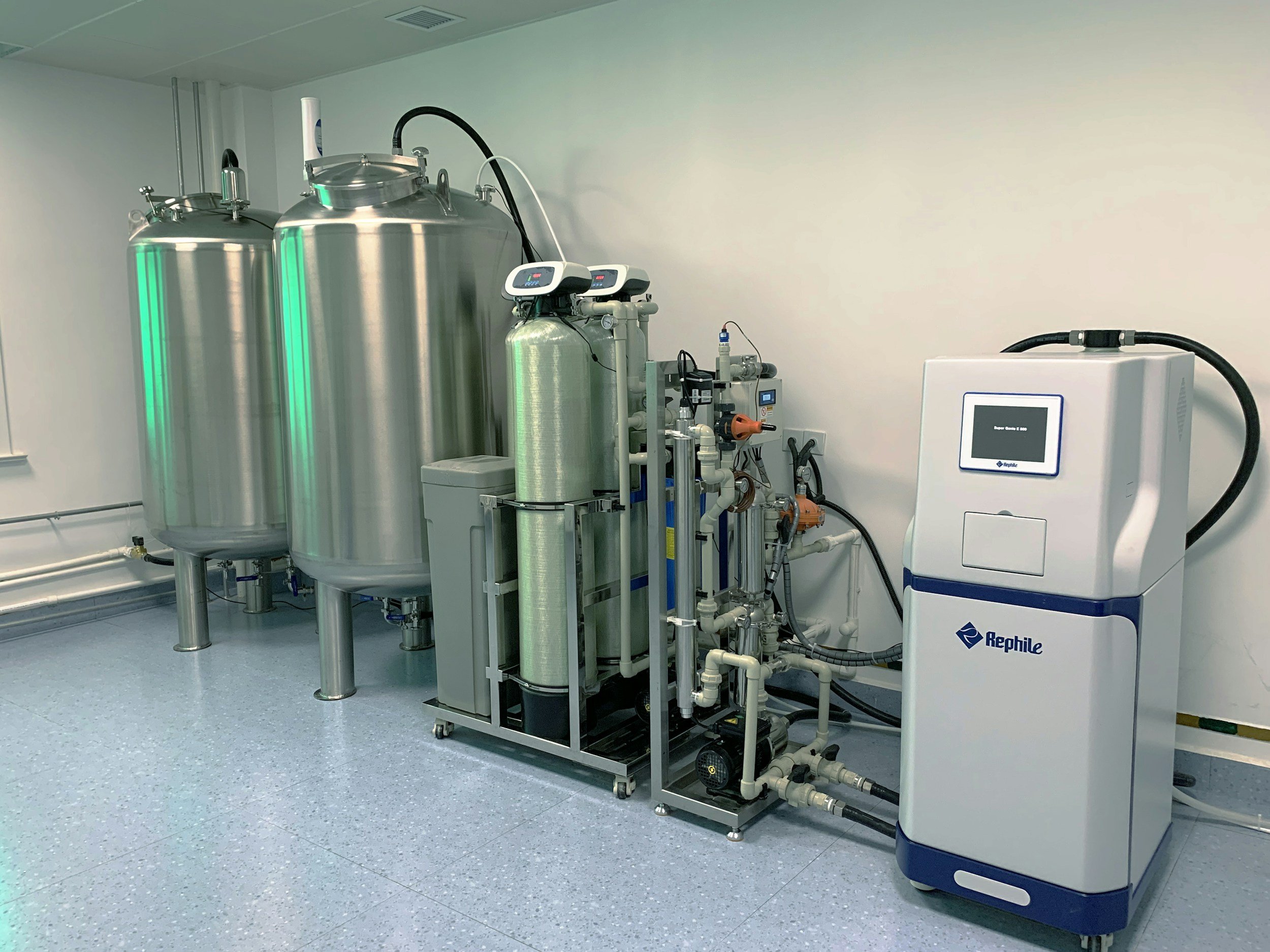 Industrial laboratory room with stainless steel tanks, pipes, and a Rephile sterilizer machine, with a white wall. Industrial electrical service in central Oregon and Oregon coast.