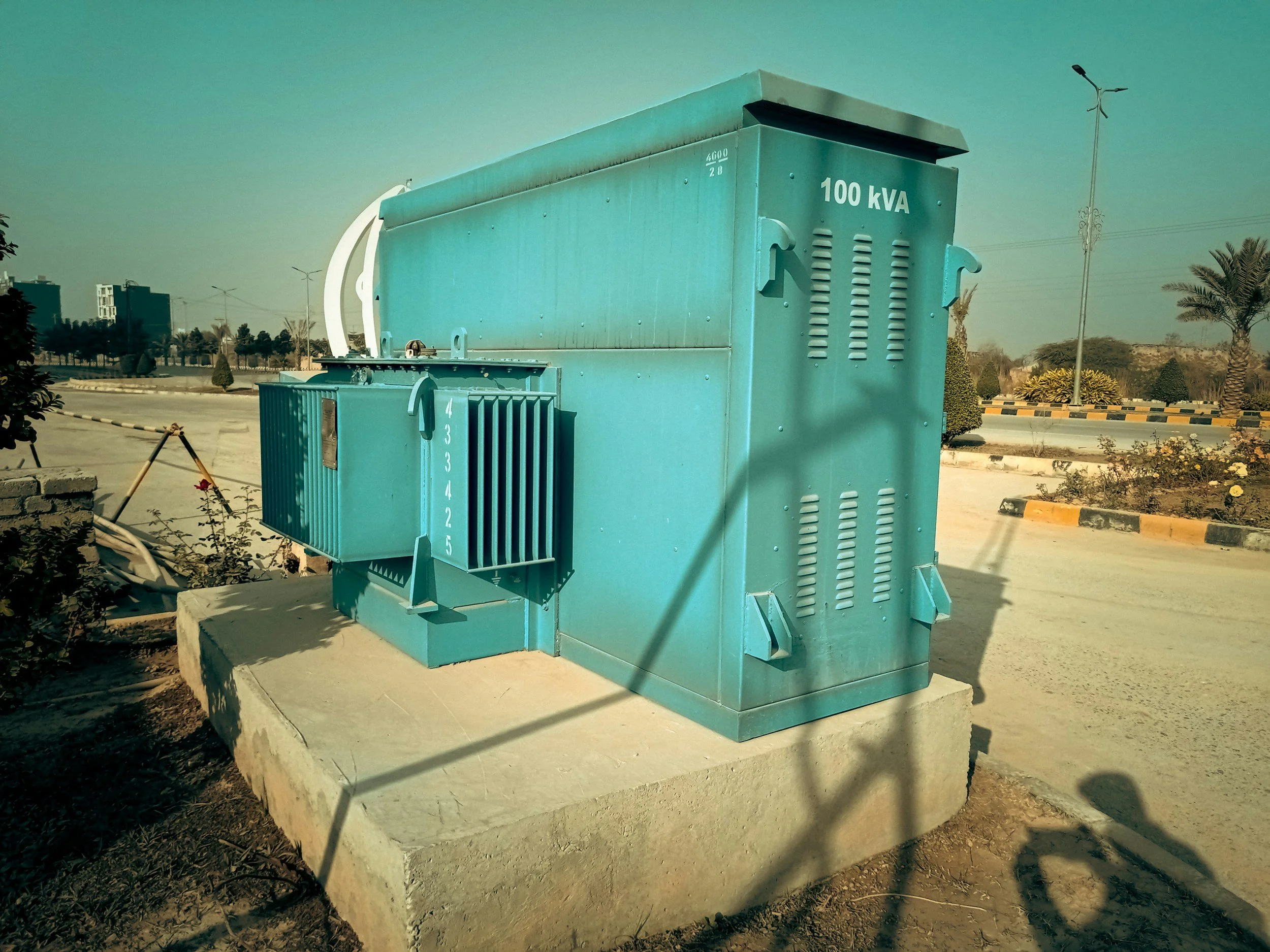 Electrical transformer painted in teal color, installed on a concrete base in an outdoor setting. Generator and standby power services in Oregon