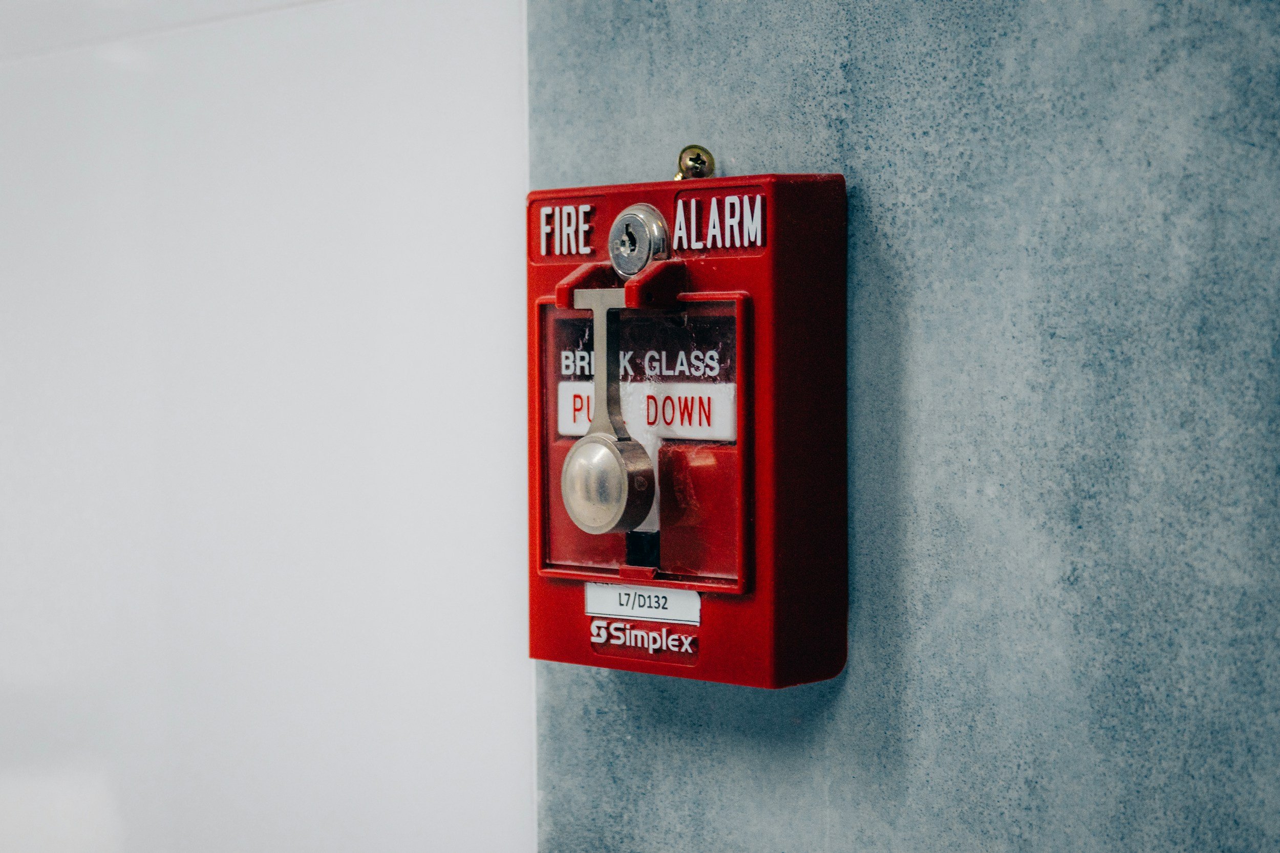 Red fire alarm manual pull station mounted on a gray wall. Limited energy and structured cabling services in Oregon