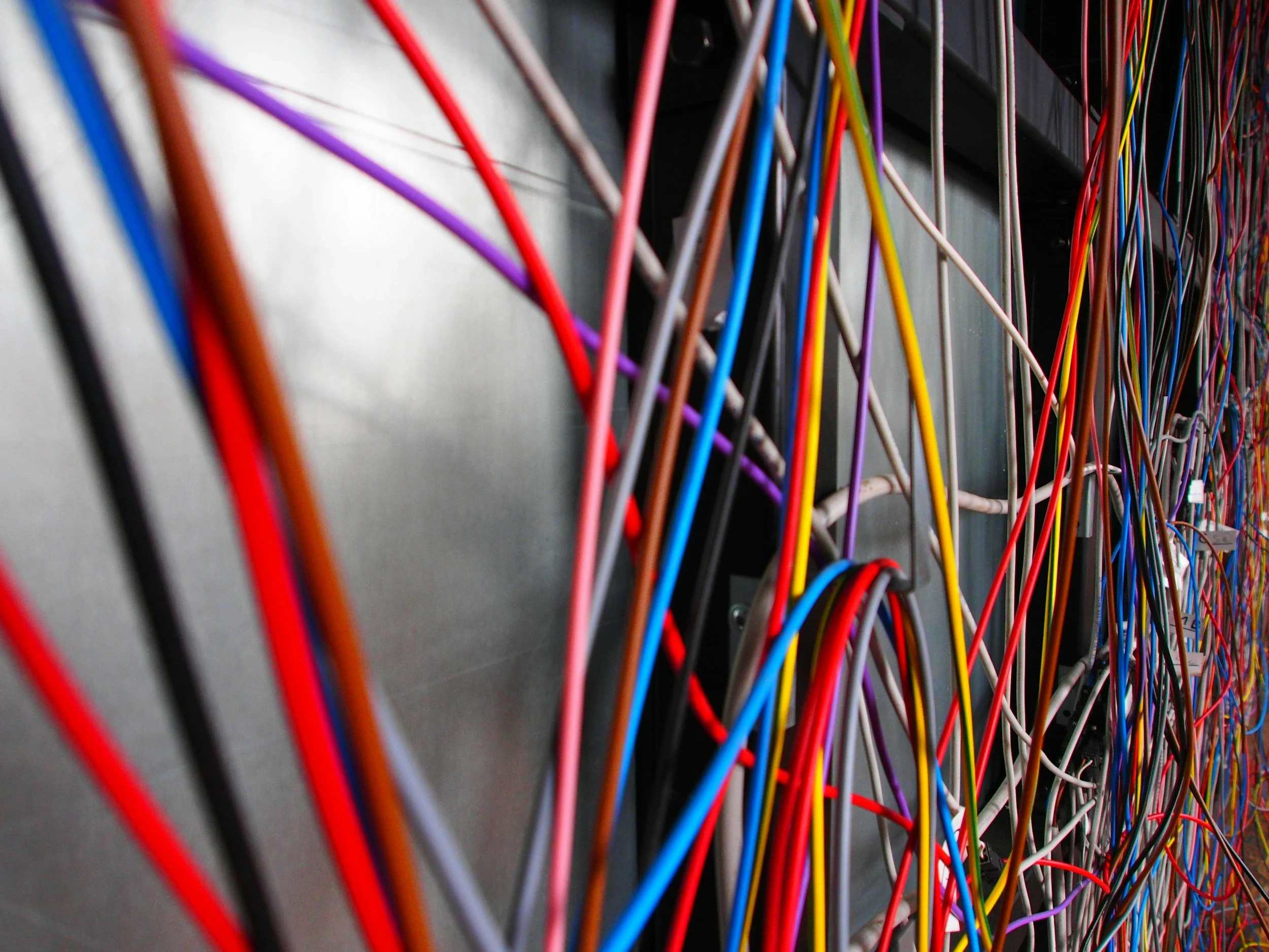 Close-up view of a network server rack with numerous colorful Ethernet cables connected to it. Cable testing service in Oregon.