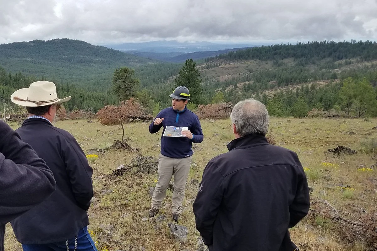 A group of stakeholders talking with mountains in the background