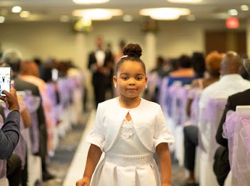 Granddaughter of Marie (Owner) walking down aisle at an elegant Wedding ceremony planned and coordinated by MPR Events LLC, with seated guests on either side.
