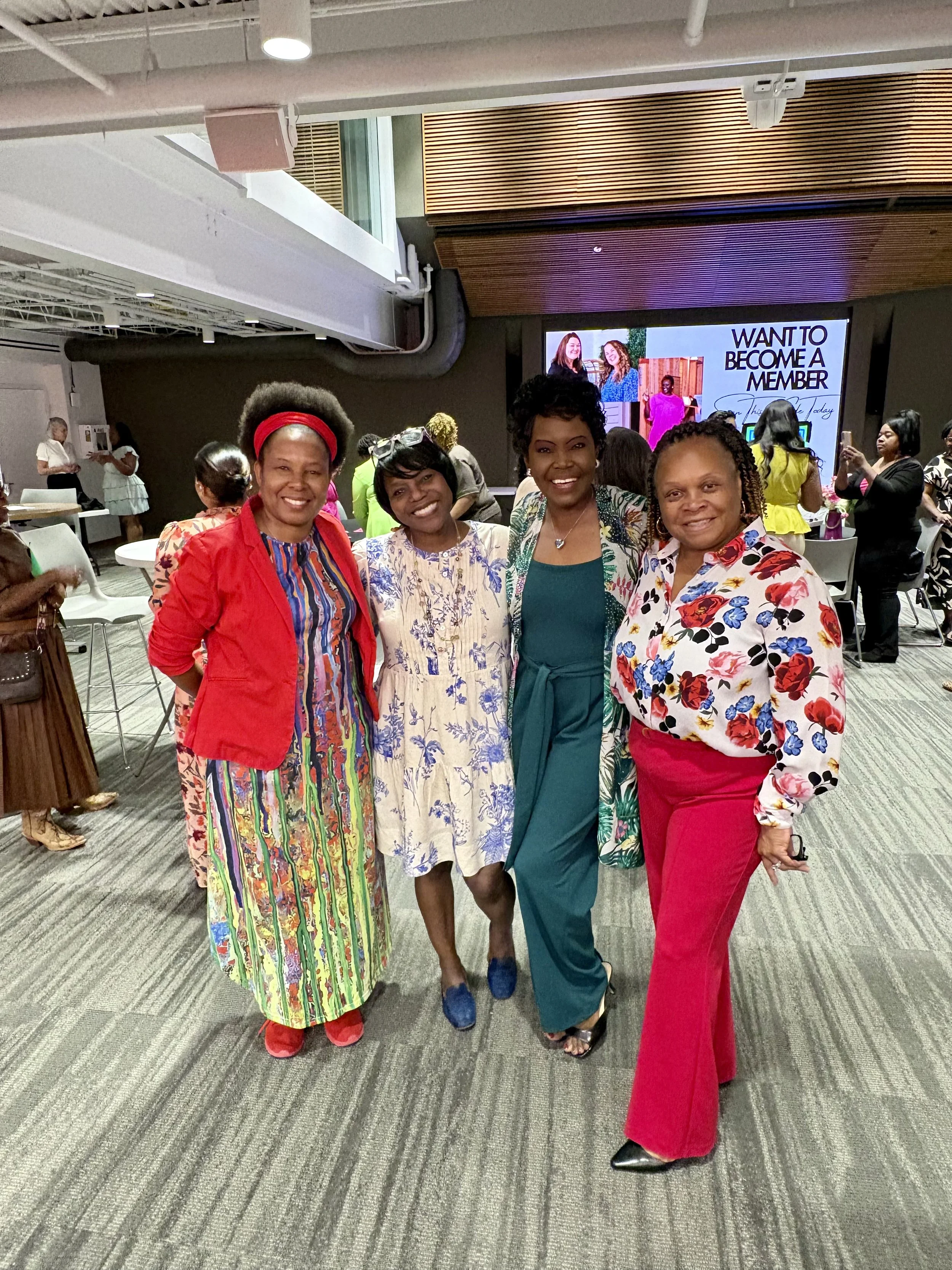 Marie (Owner) in green, smiling and joyful with group of woman at a Tallahassee networking event.