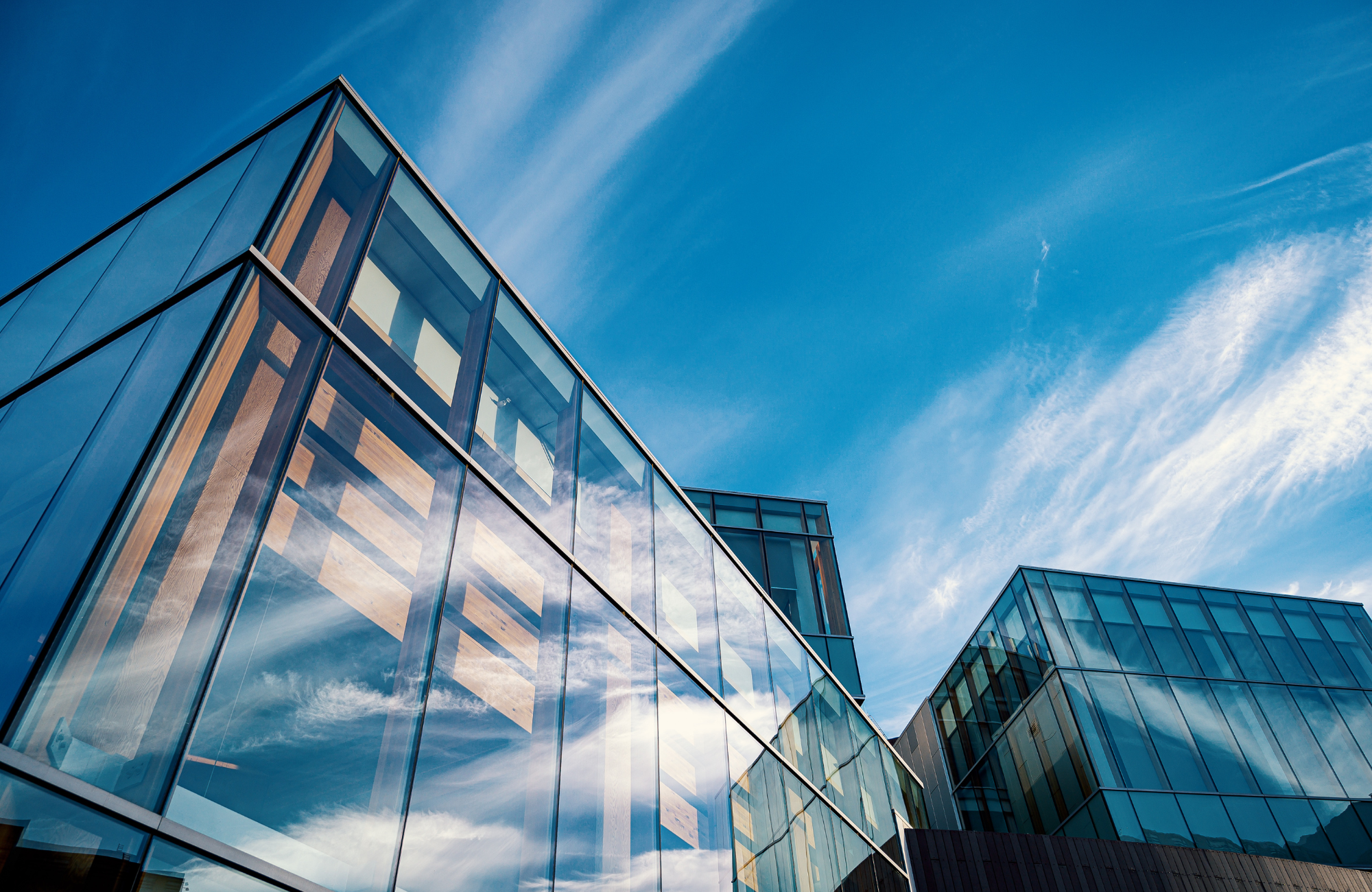 Modern glass building with reflections of the sky and clouds on its surface.