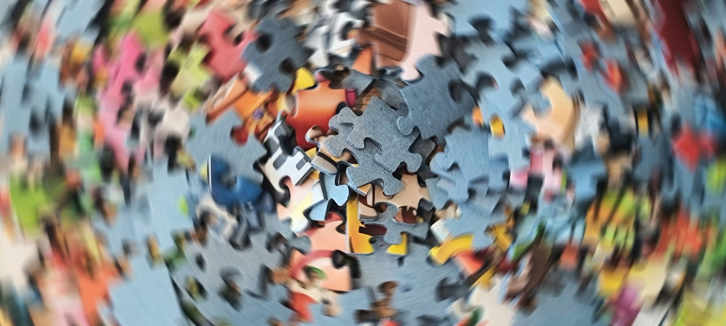 Colorful jigsaw puzzle pieces scattered, with some assembled sections visible.
