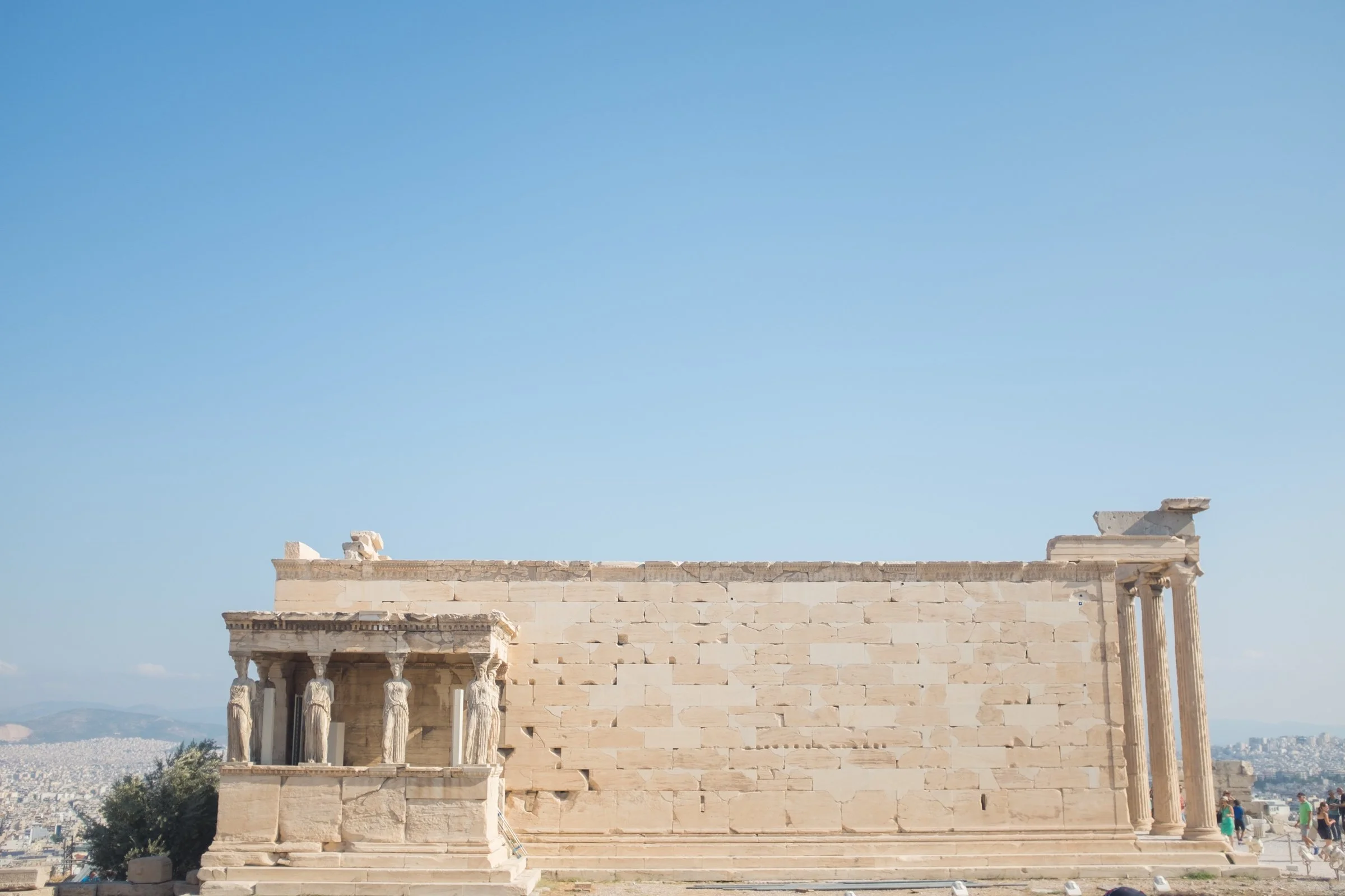 Ancient Greek ruins with columns and steps in front of a clear blue sky, likely part of a historic temple or building.