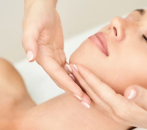 Person receiving a facial massage or skin treatment with close-up of their face and hands of the practitioner