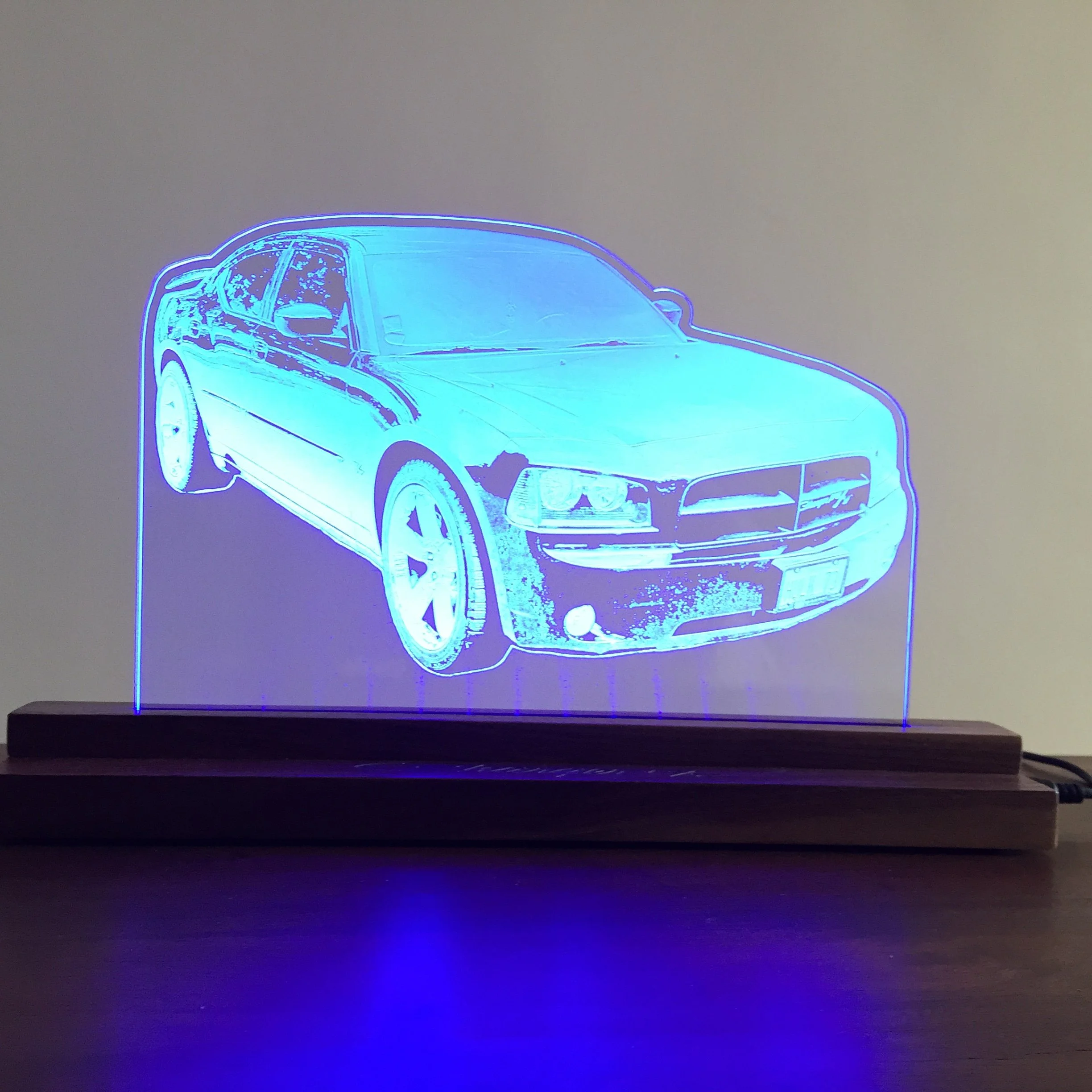  Neon outline of a sports car displayed on a wall with blue and purple lighting.