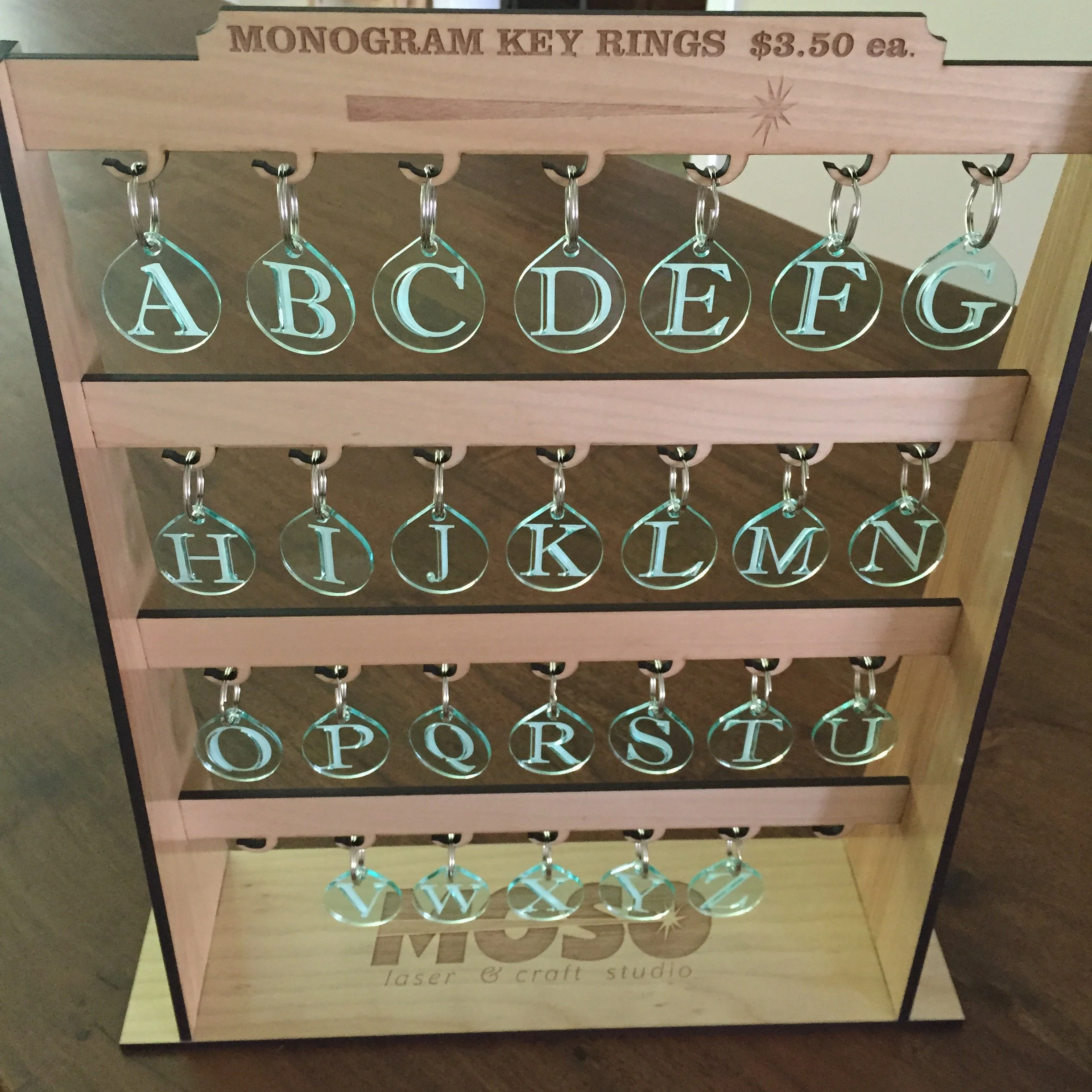 A wooden display stand with metal key rings featuring engraved alphabet letters