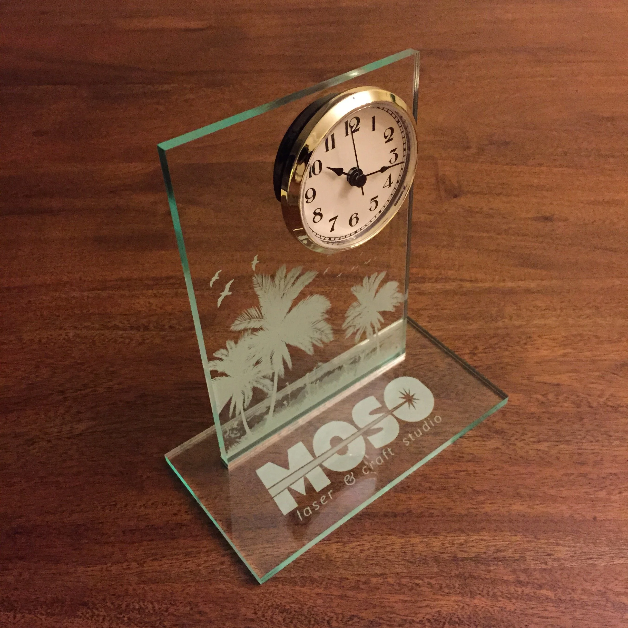 A glass trophy with engraved text and a design of dandelions and a star burst.