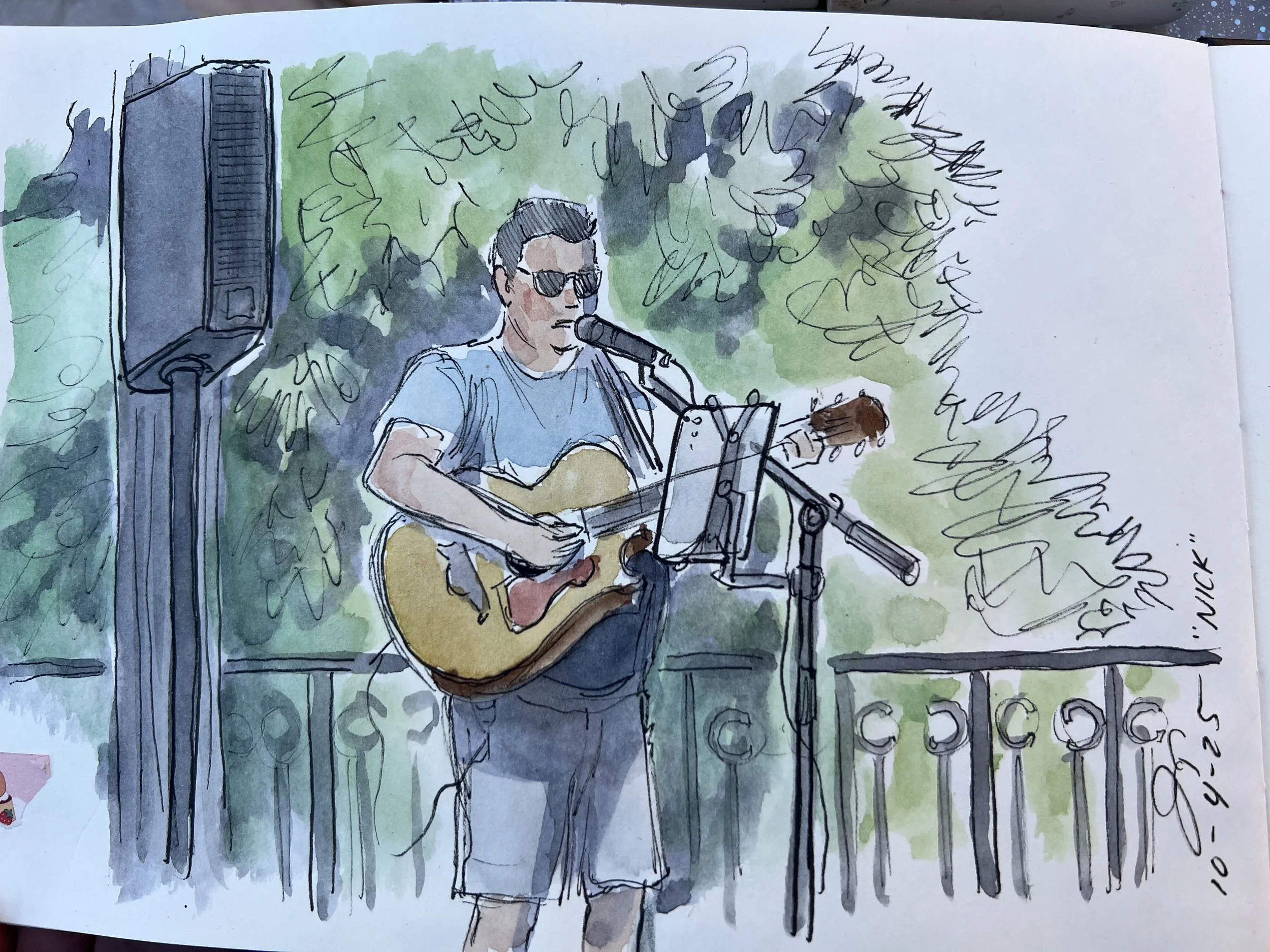 A watercolor sketch of a man wearing sunglasses and a blue shirt, holding an acoustic guitar, standing outdoors on a sunny day with lush green trees in the background, and a speaker to the left.