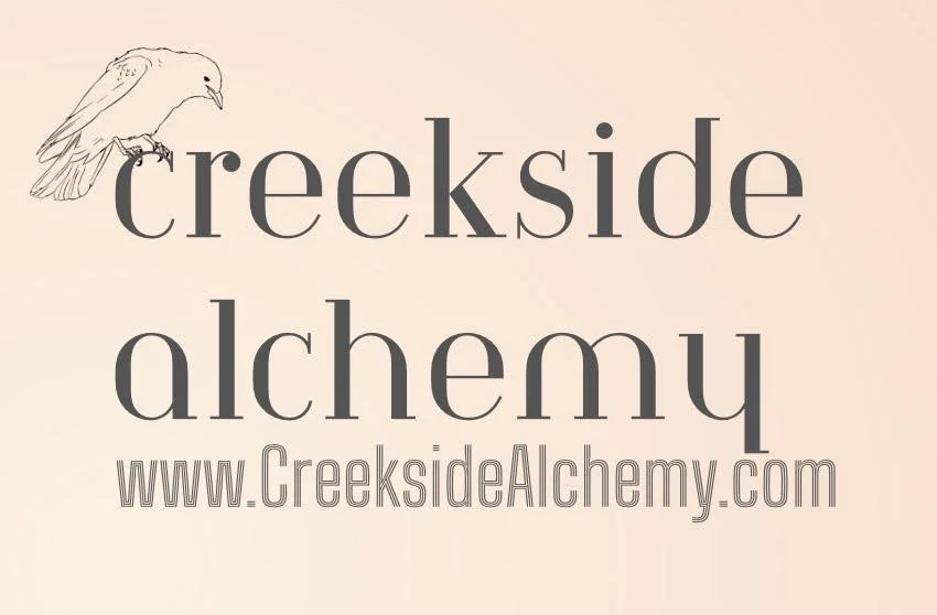 A minimalist logo for Creekside Alchemy featuring a sketch of a bird perched on the word 'creekside' with 'alchemy' written below and the website URL www.CreeksideAlchemy.com at the bottom.