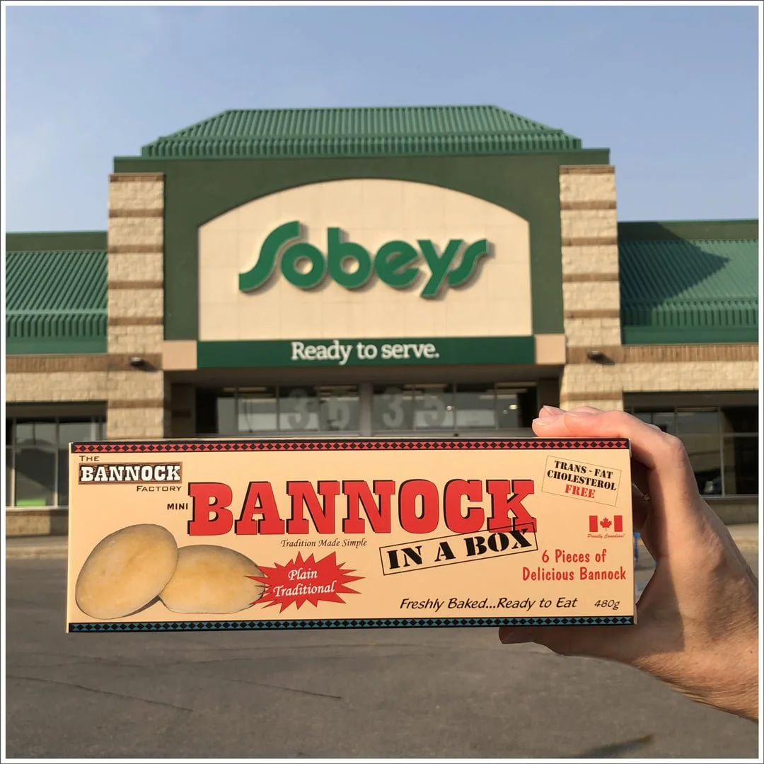 A person holding a box of Bannock in front of a Sobeys store with the slogan 'Ready to serve.'