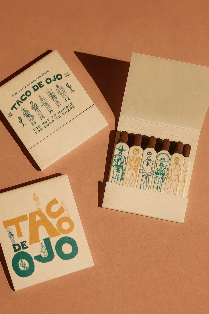 Open matchbox containing four cigar samples with colorful illustrated characters on the wrappers, placed beside closed boxes labeled 'Taco de Ojo' with playful text and illustration of figures.