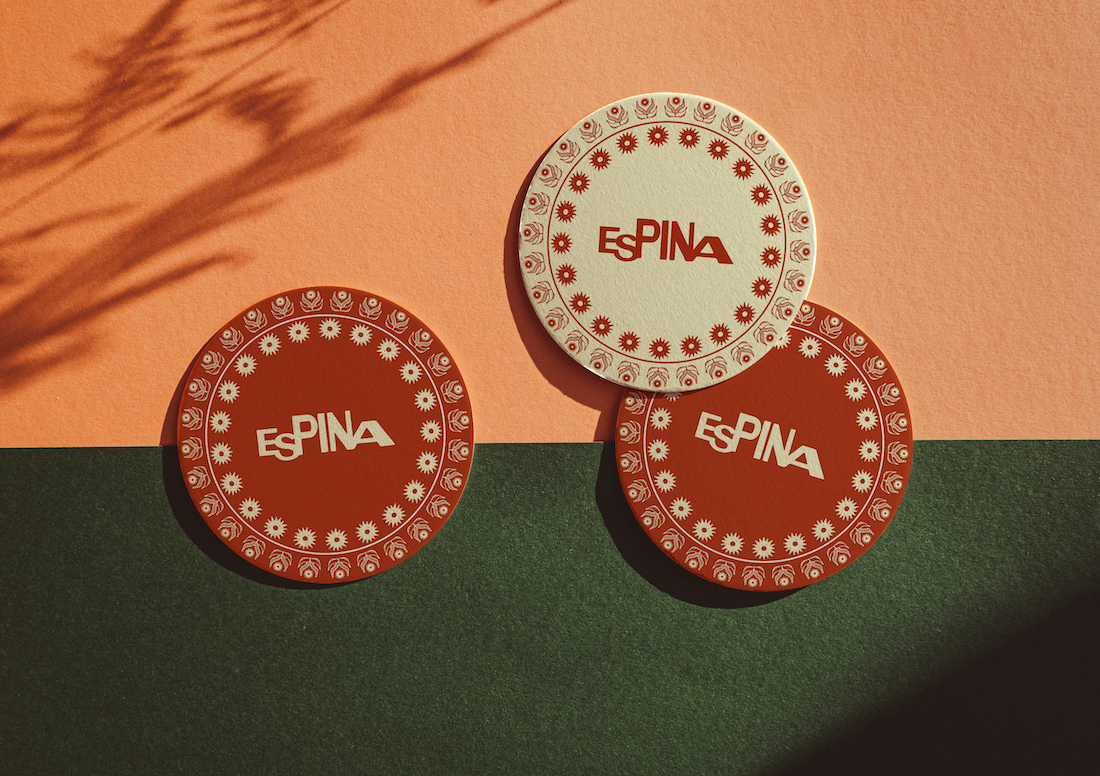 Three casino chips with the text 'ESpINA' on them, placed on a surface with green and beige sections, and a shadow cast over the beige background.