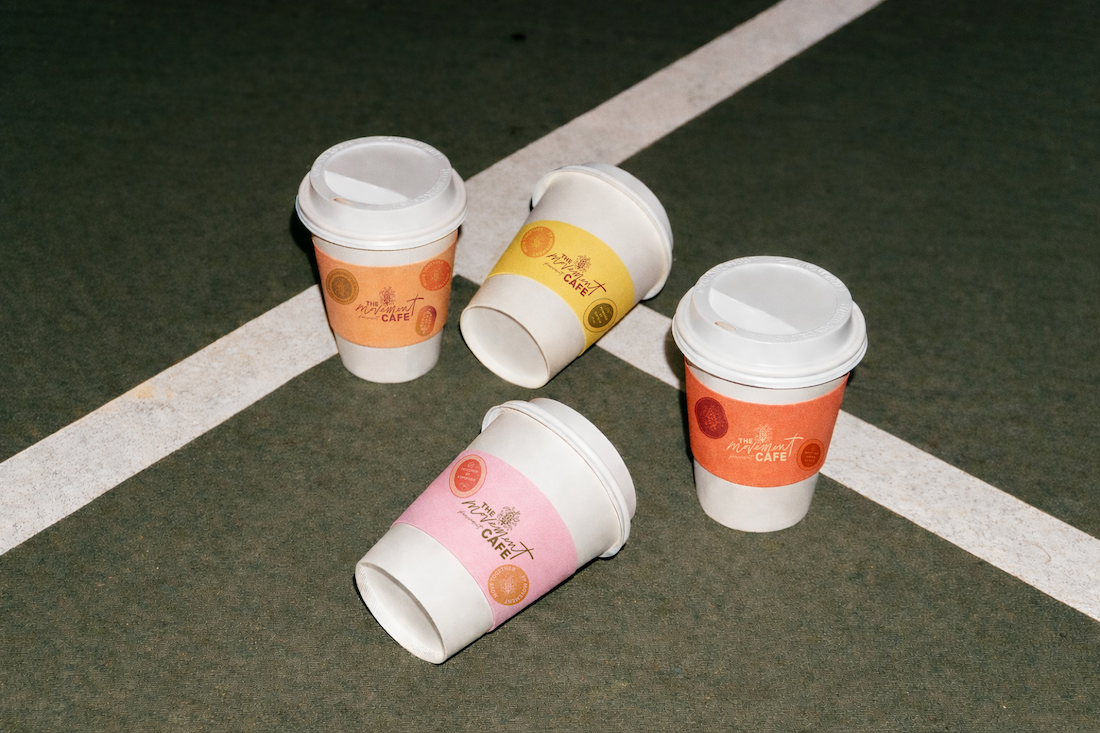 Four disposable coffee cups with colorful sleeves on a dark outdoor surface, some lying on their sides.